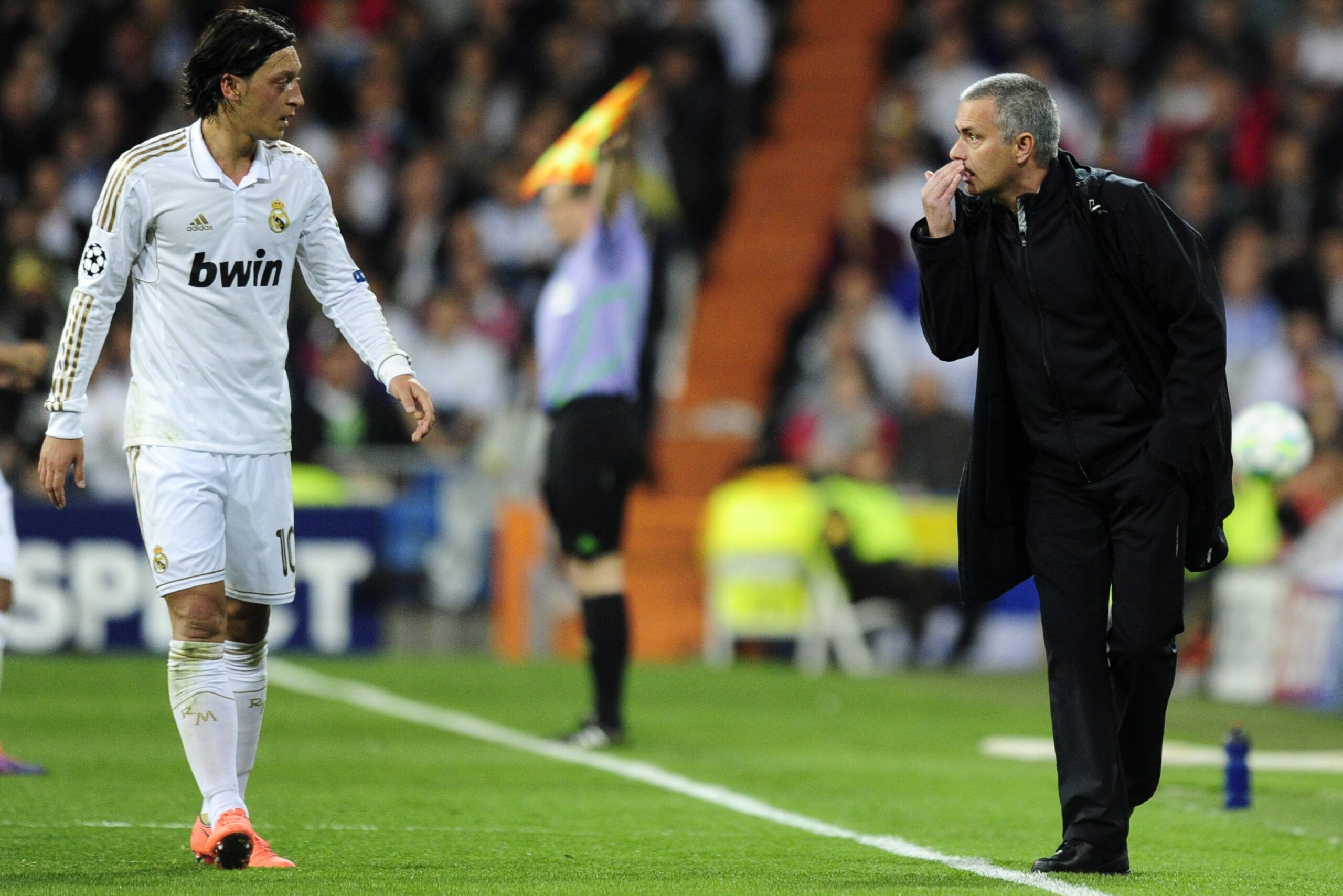 Real Madrid's Portuguese coach Jose Mourinho (R) speaks with Real Madrid's German midfielder Mesut Ozil during the UEFA Champions League second leg semi-final football match Real Madrid against Bayern Munich  at the Santiago Bernabeu stadium in Madrid on 