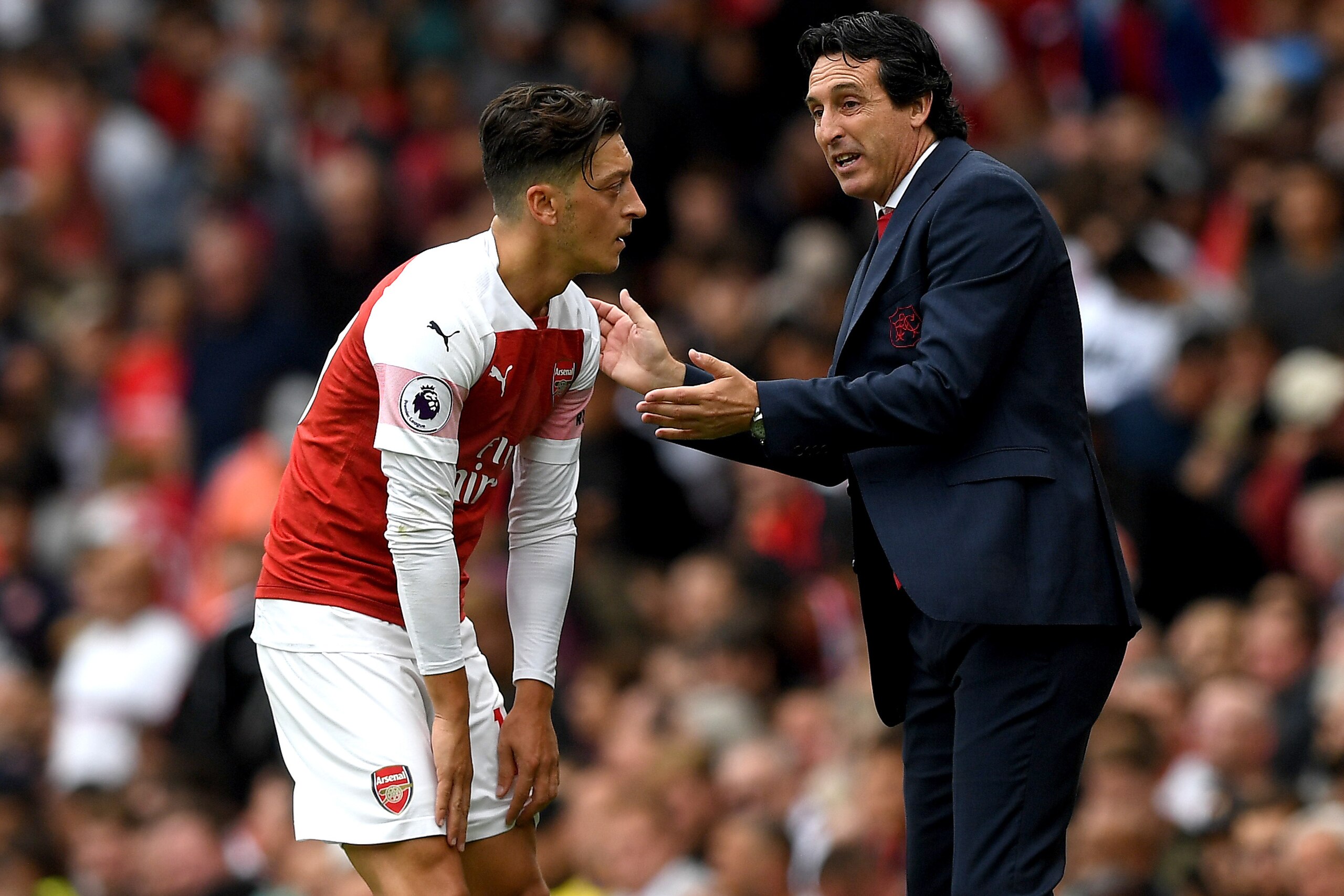 LONDON, ENGLAND - AUGUST 12:  Unai Emery, Manager of Arsenal speaks with Mesut Ozil of Arsenal during the Premier League match between Arsenal FC and Manchester City at Emirates Stadium on August 12, 2018 in London, United Kingdom.  (Photo by Shaun Botter