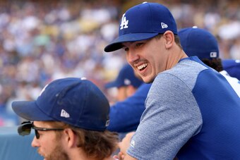 LOS ANGELES, CA - OCTOBER 01:  Walker Buehler #21 of the Los Angeles Dodgers laughs with Clayton Kershaw #22 in the dugout, in the eighth inning, during a 5-2 win over the Colorado Rockies during the National League West tiebreaker game at Dodger Stadium 