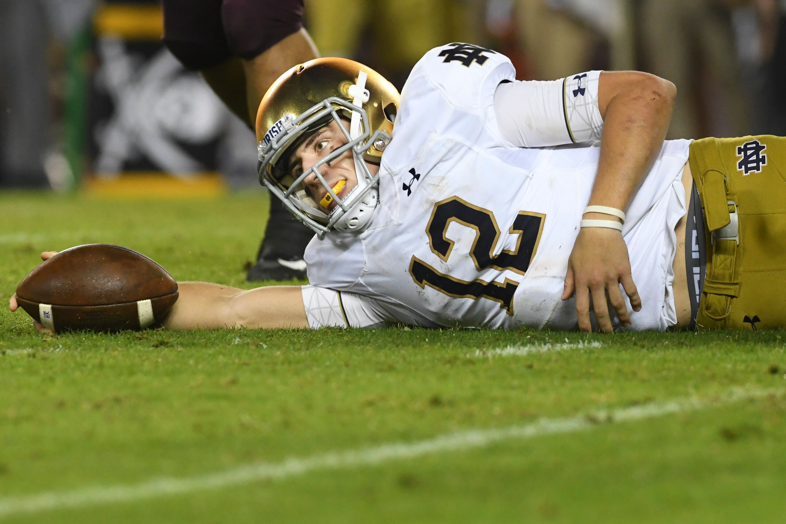 BLACKSBURG, VA - OCTOBER 6: Quarterback Ian Book #12 of the Notre Dame Fighting Irish reaches for extra yards after being tackled against the Virginia Tech Hokies in the second half at Lane Stadium on October 6, 2018 in Blacksburg, Virginia. (Photo by Mic