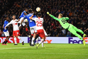 Spartak Moscow's Russian goalkeeper Aleksandr Maksimenko (R) dives to bunch the ball clear during the UEFA Europa League Group G football match between Rangers and Spartak Moscow at Ibrox Stadium in Glasgow on October 25, 2018. (Photo by ANDY BUCHANAN / A