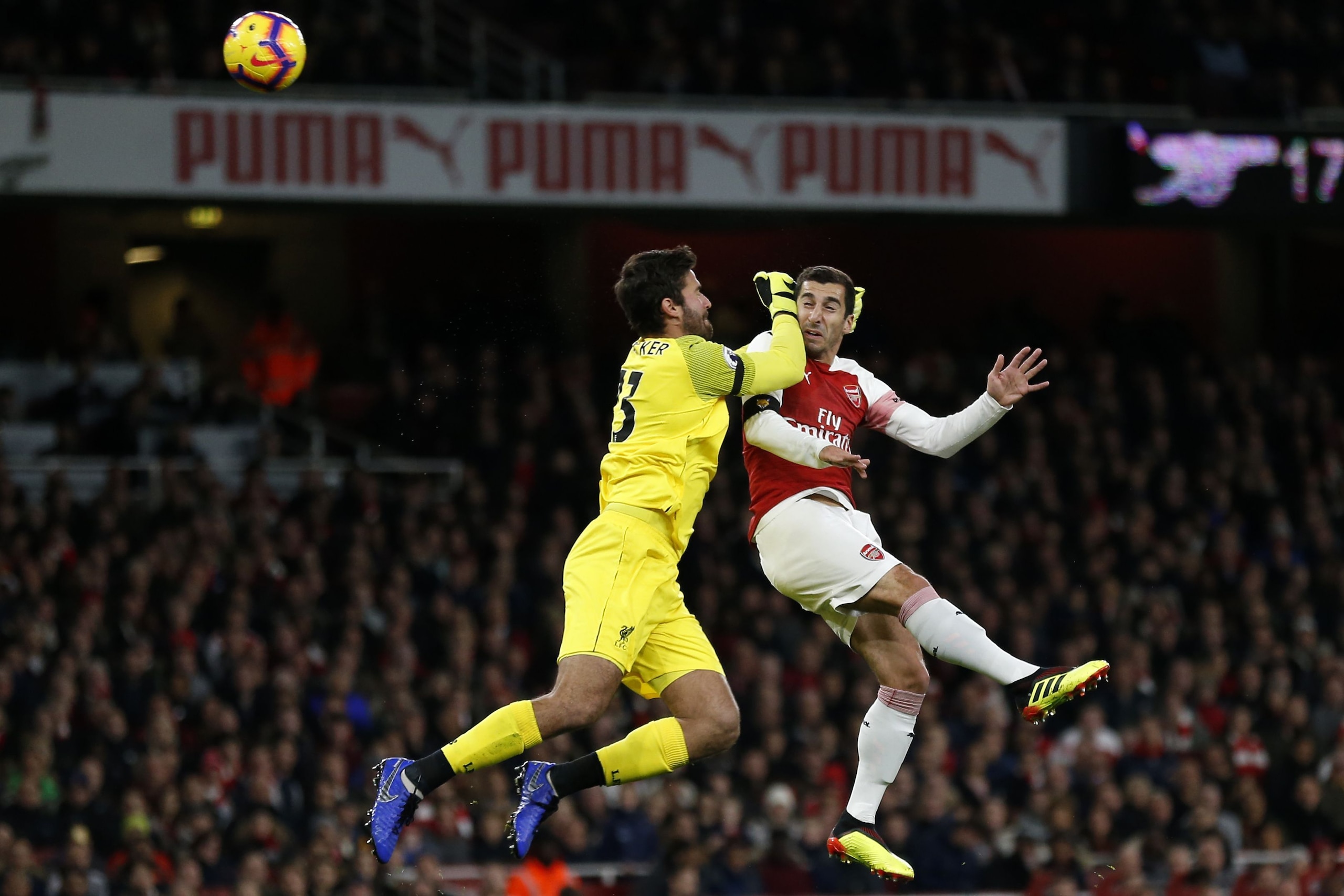 TOPSHOT - Arsenal's Armenian midfielder Henrikh Mkhitaryan (R) heads wide as Liverpool's Brazilian goalkeeper Alisson Becker comes out to challenge during the English Premier League football match between Arsenal and Liverpool at the Emirates Stadium in L