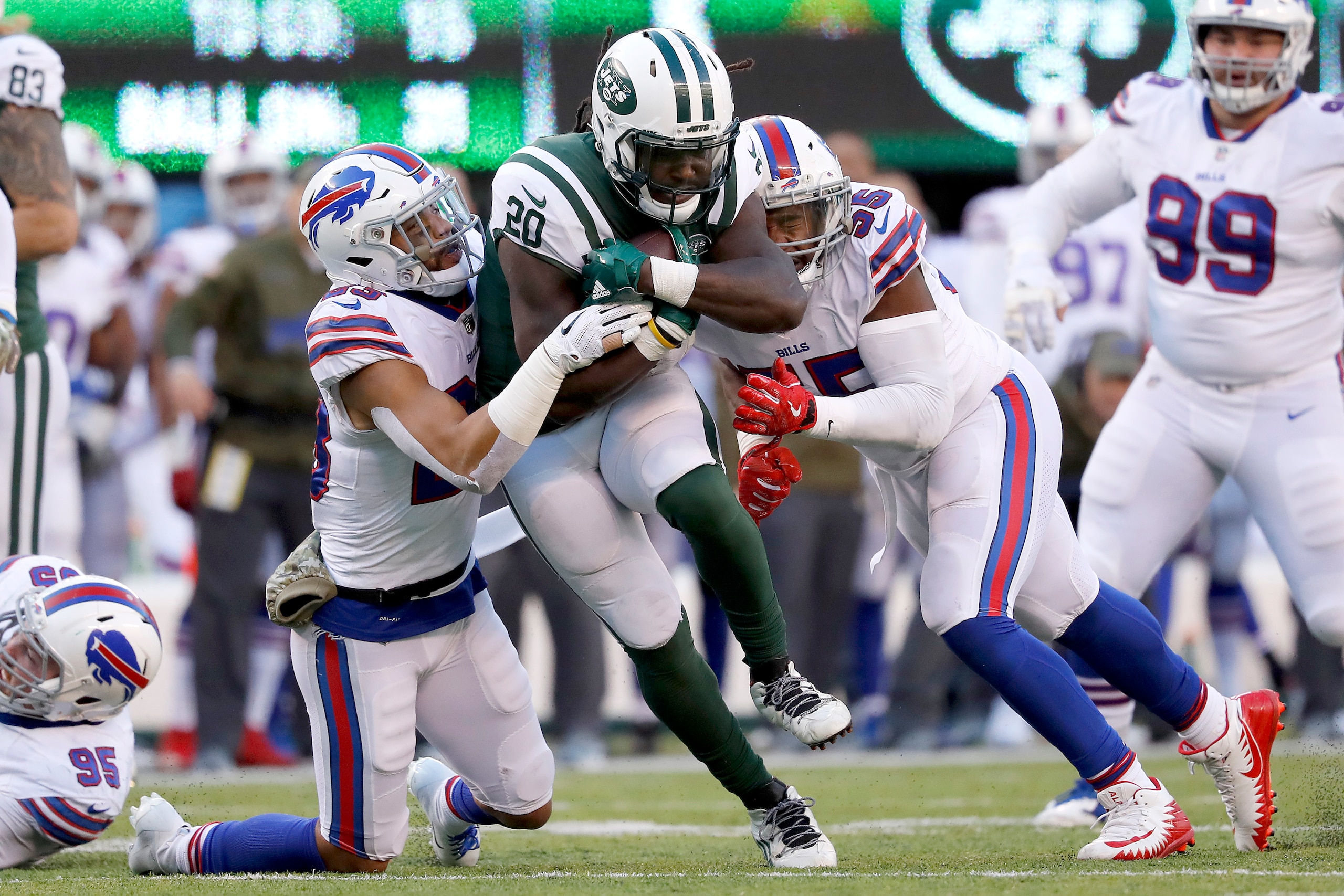 EAST RUTHERFORD, NEW JERSEY - NOVEMBER 11: Isaiah Crowell #20 of the New York Jets is tackled by Micah Hyde #23 and Jerry Hughes #55 of the Buffalo Bills during the third quarter at MetLife Stadium on November 11, 2018 in East Rutherford, New Jersey. (Pho