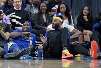 LAS VEGAS, NEVADA - OCTOBER 10:  Kevin Durant (L) #35 and DeMarcus Cousins #0 of the Golden State Warriors share a laugh as they sit on a baseline during their preseason game against the Los Angeles Lakers at T-Mobile Arena on October 10, 2018 in Las Vega