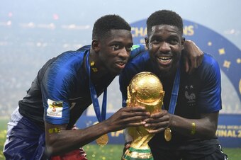 France's forward Ousmane Dembele (L) and France's defender Samuel Umtiti pose with the World Cup trophy after the Russia 2018 World Cup final football match between France and Croatia at the Luzhniki Stadium in Moscow on July 15, 2018. (Photo by FRANCK FI