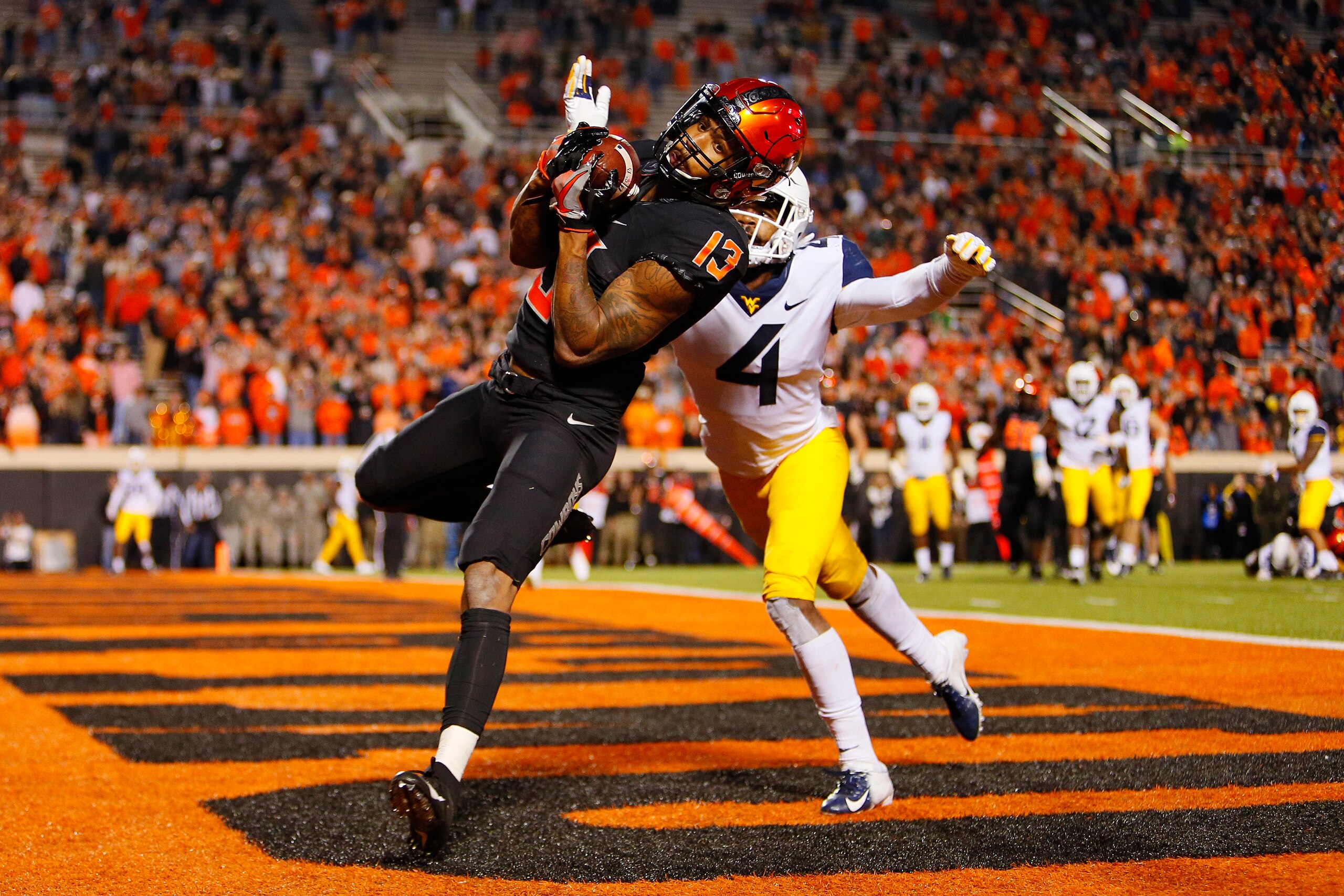 STILLWATER, OK - NOVEMBER 17:  Wide receiver Tyron Johnson #13 of the Oklahoma State Cowboys pulls down a touchdown catch against cornerback Josh Norwood #4 of the West Virginia Mountaineers in the fourth quarter on November 17, 2018 at Boone Pickens Stad