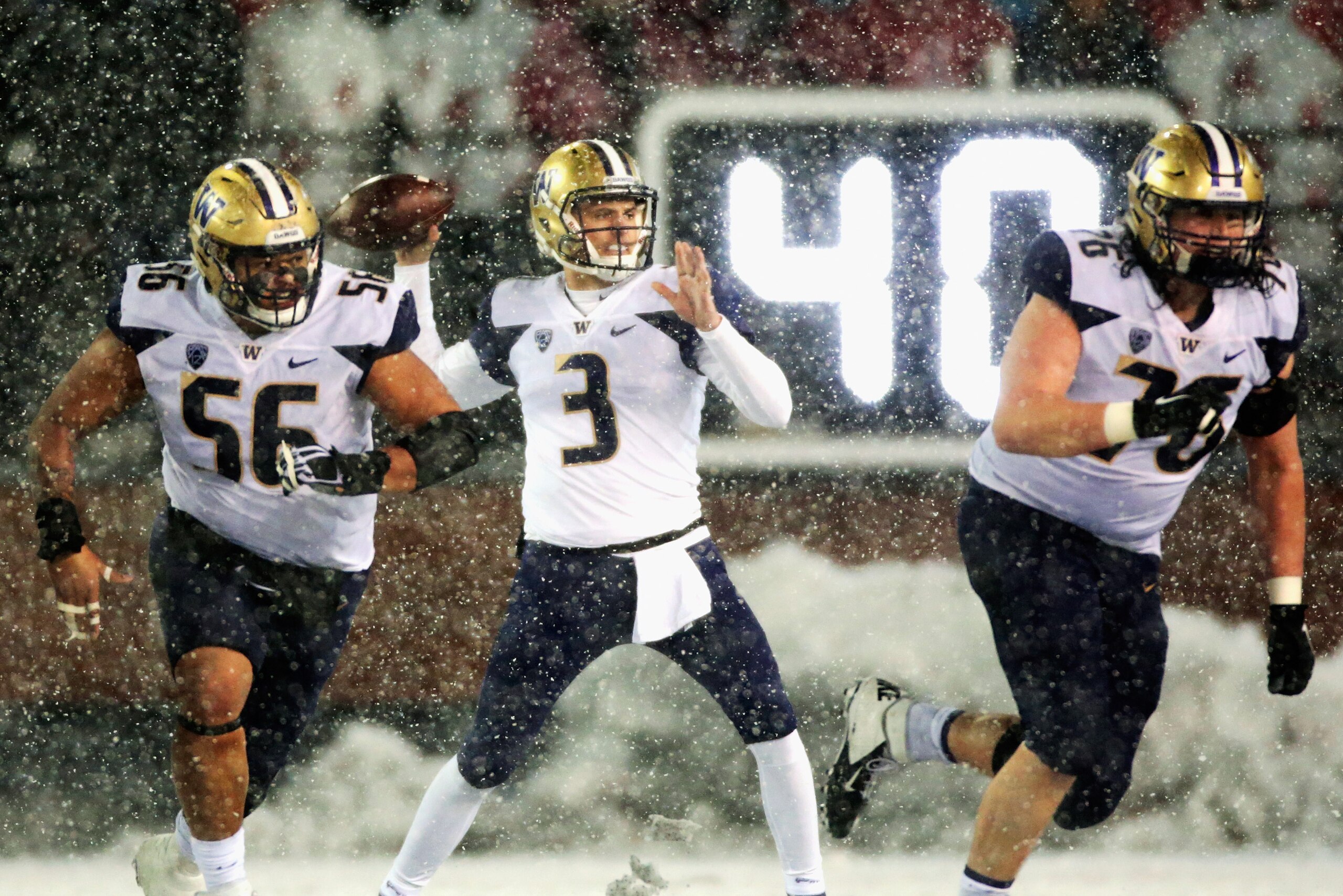 PULLMAN, WA - NOVEMBER 23:  Quarterback Jake Browning #3 throws a pass while be defefended by Nick Harris #56 and Luke Wattenberg #76 of the Washington Huskies in the second half against the Washington State Cougars at Martin Stadium during the 111th Appl