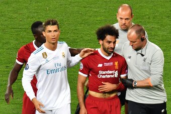 Liverpool's Egyptian forward Mohamed Salah (3rd R) is comforted by team members and Real Madrid's Portuguese forward Cristiano Ronaldo (2nd L) as he leaves the pitch after injury during the UEFA Champions League final football match between Liverpool and 