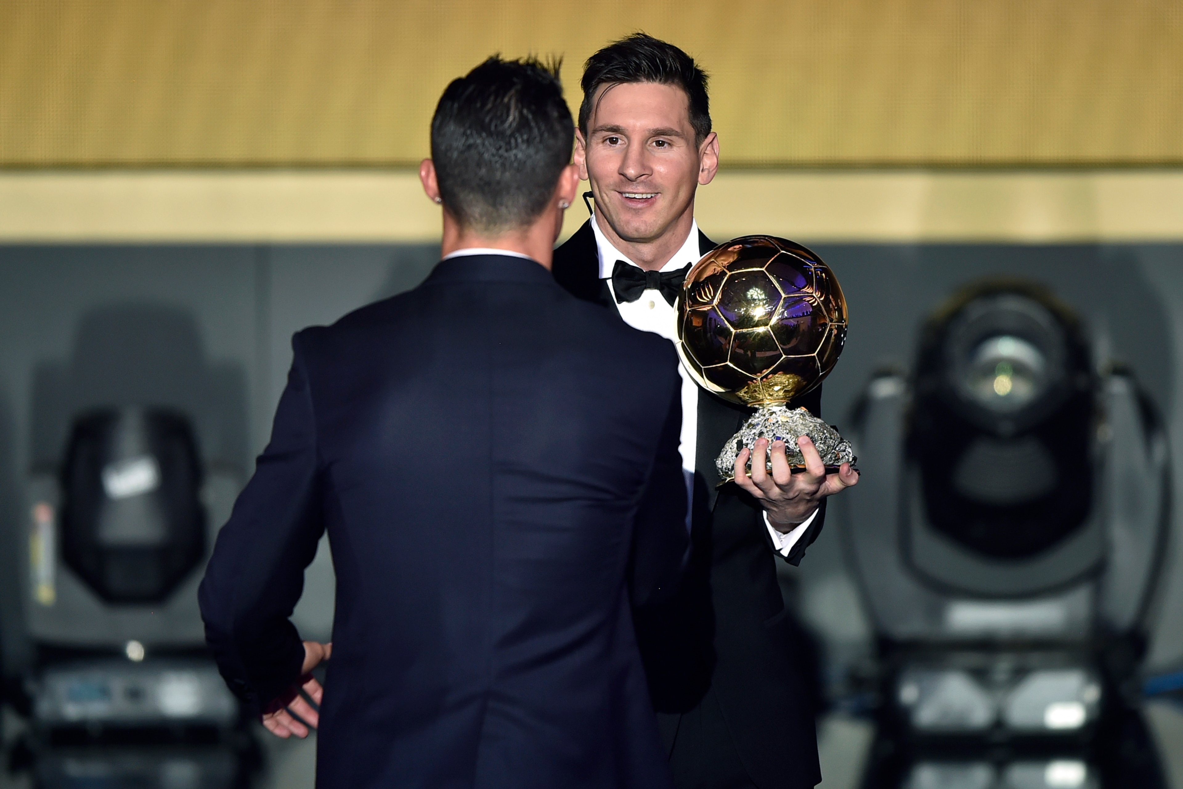 FC Barcelona and Argentina's forward Lionel Messi (R) holds his trophy as he shakes hands with Real Madrid and Portugal's forward  Cristiano Ronaldo after receiving the 2015 FIFA Ballon dOr award for player of the year during the 2015 FIFA Ballon d'Or awa