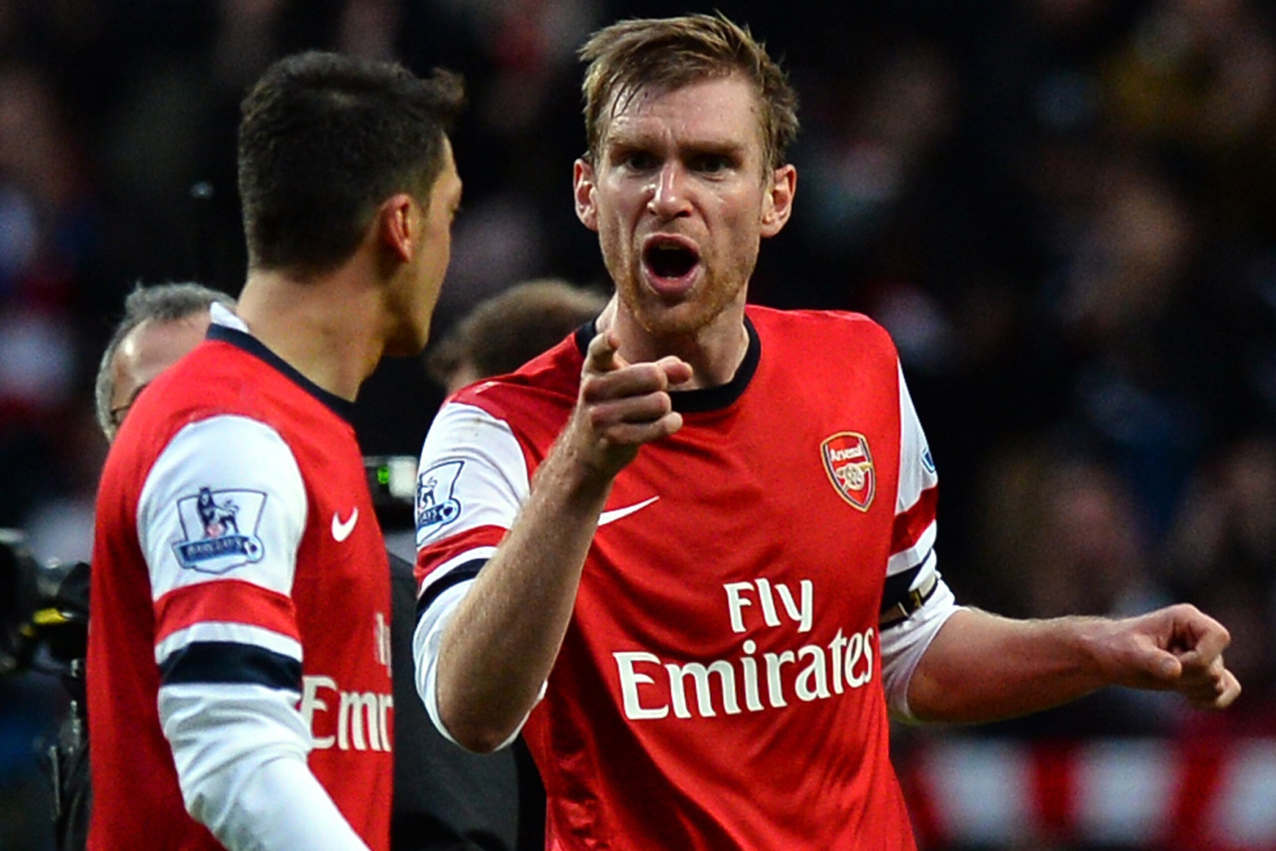 Arsenal's German defender Per Mertesacker (R) argues with German midfielder Mesut Ozil (L) after the final whistle of the English Premier League football match between Manchester City and Arsenal at the Etihad Stadium in Manchester, northwest England, on 
