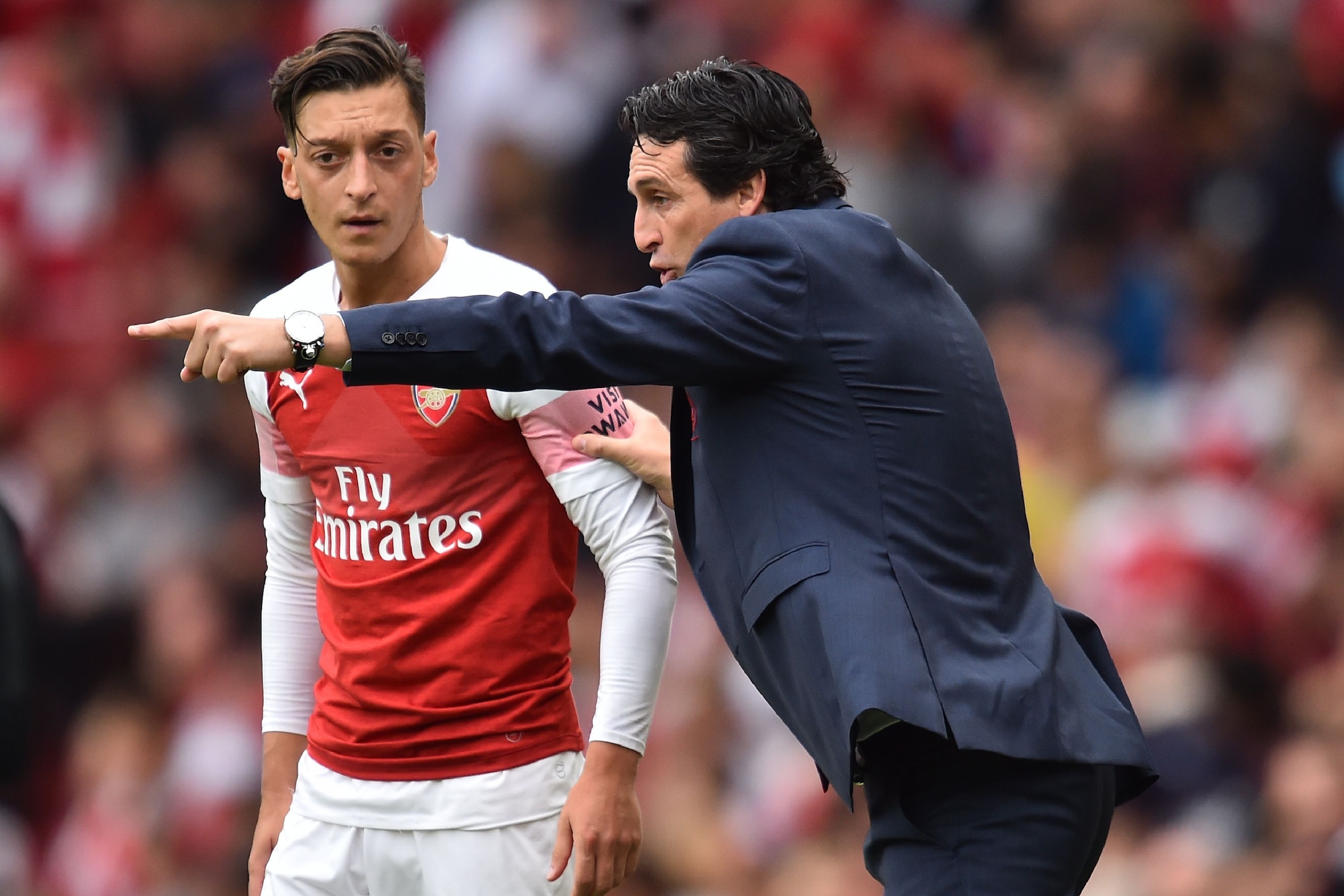 Arsenal's Spanish head coach Unai Emery gestures to Arsenal's German midfielder Mesut Ozil (L) on the touchline during the English Premier League football match between Arsenal and Manchester City at the Emirates Stadium in London on August 12, 2018. (Pho