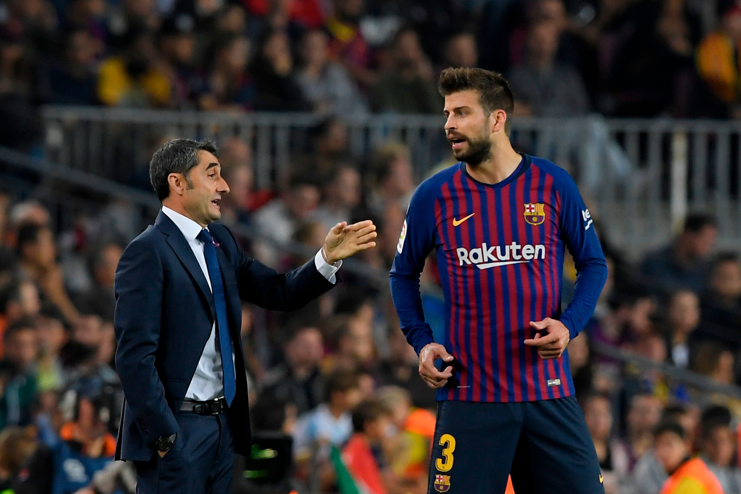 Barcelona's Spanish coach Ernesto Valverde (L) speaks to Barcelona's Spanish defender Gerard Pique during the Spanish league football match FC Barcelona against Sevilla FC at the Camp Nou stadium in Barcelona on October 20, 2018. (Photo by LLUIS GENE / AF