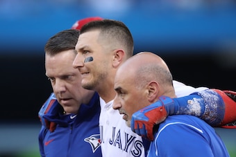 TORONTO, ON - JULY 28: Troy Tulowitzki #2 of the Toronto Blue Jays is helped off the field by trainers George Poulis and Mike Frostad after injuring his ankle in the third inning during MLB game action against the Los Angeles Angels of Anaheim at Rogers C