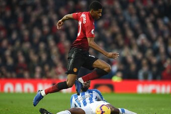 Manchester United's English striker Marcus Rashford (top) jumps a challenge from Huddersfield Town's Belgian striker Isaac Mbenza (bottom) during the English Premier League football match between Manchester United and Huddersfield Town at Old Trafford in 