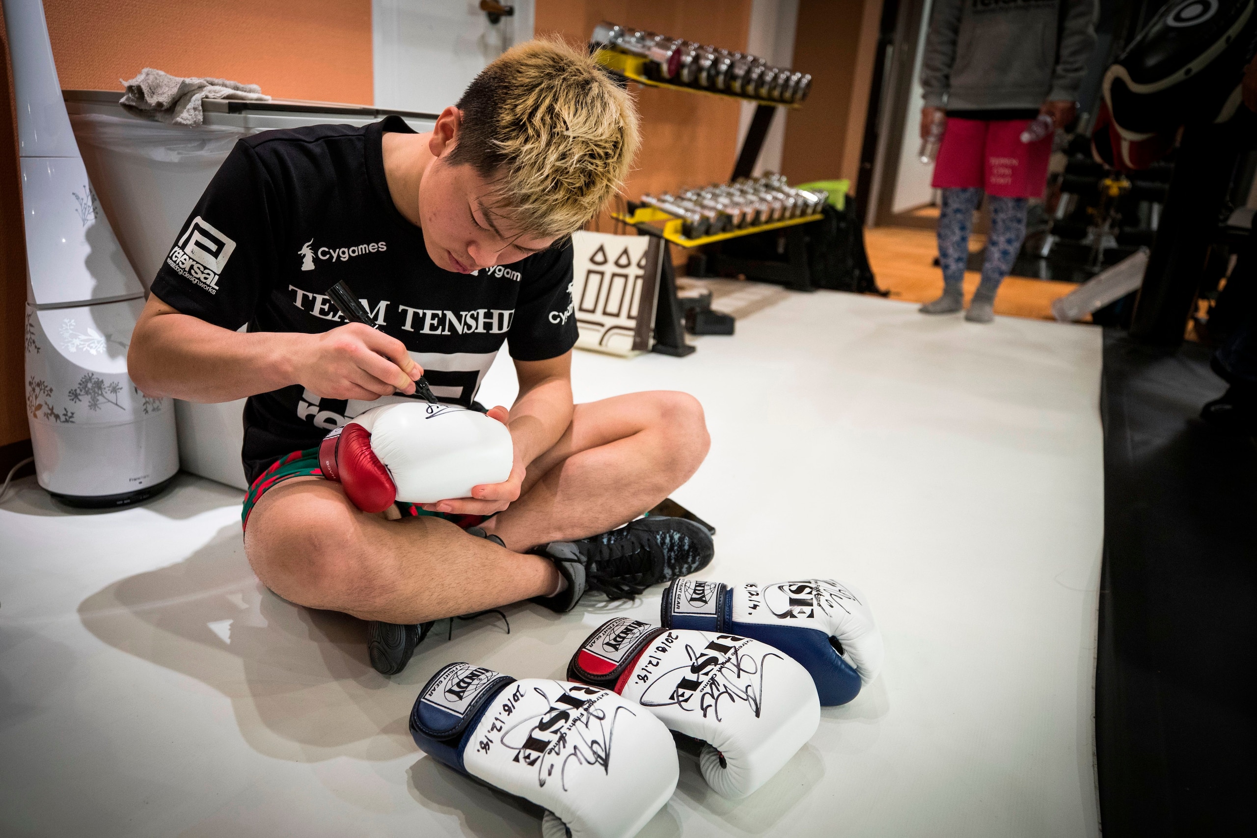 Japanese kickboxer Tenshin Nasukawa signs some boxing gloves after a training session in front of the media at his boxing gym in Matsuda, Chiba prefecture on December 18, 2018. - Japanese kickboxer Tenshin 'Ninja Boy' Nasukawa said he wants to use the ele