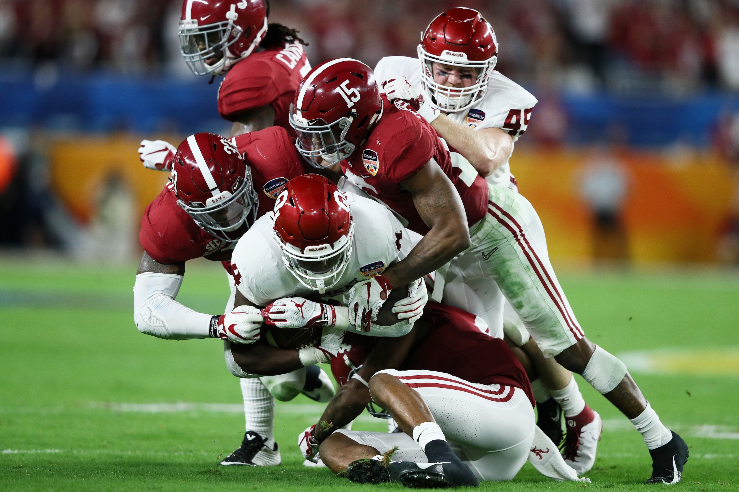MIAMI, FL - DECEMBER 29:  Trey Sermon #4 of the Oklahoma Sooners is tackled by Xavier McKinney #15 and Anfernee Jennings #33 of the Alabama Crimson Tide during the College Football Playoff Semifinal at the Capital One Orange Bowl at Hard Rock Stadium on D
