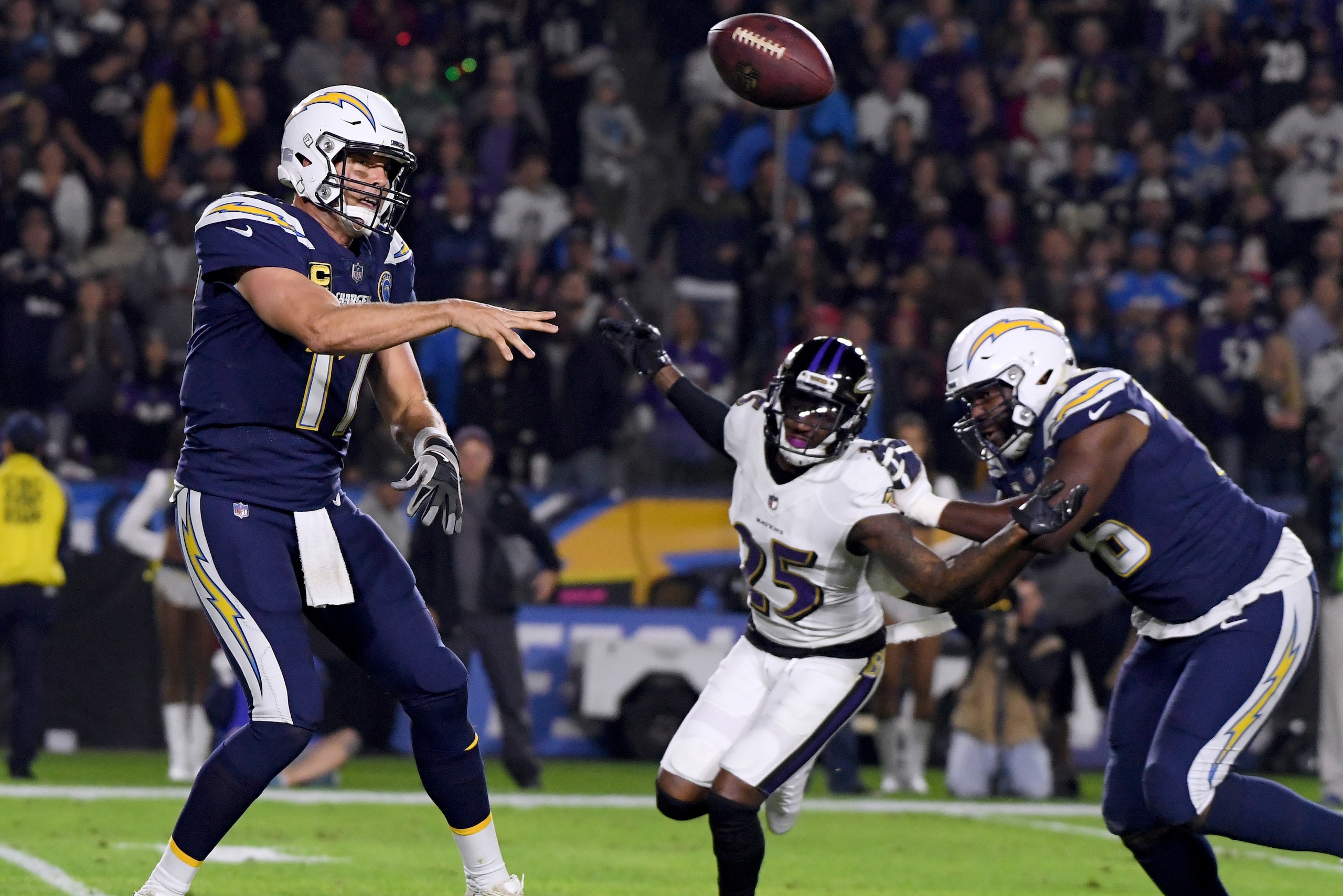 CARSON, CALIFORNIA - DECEMBER 22:   Philip Rivers #17 of the Los Angeles Chargers makes a pass on the run in front of Tavon Young #25 of the Baltimore Ravens and Russell Okung #76 during the second quarter in a 22-10 Ravens win at StubHub Center on Decemb