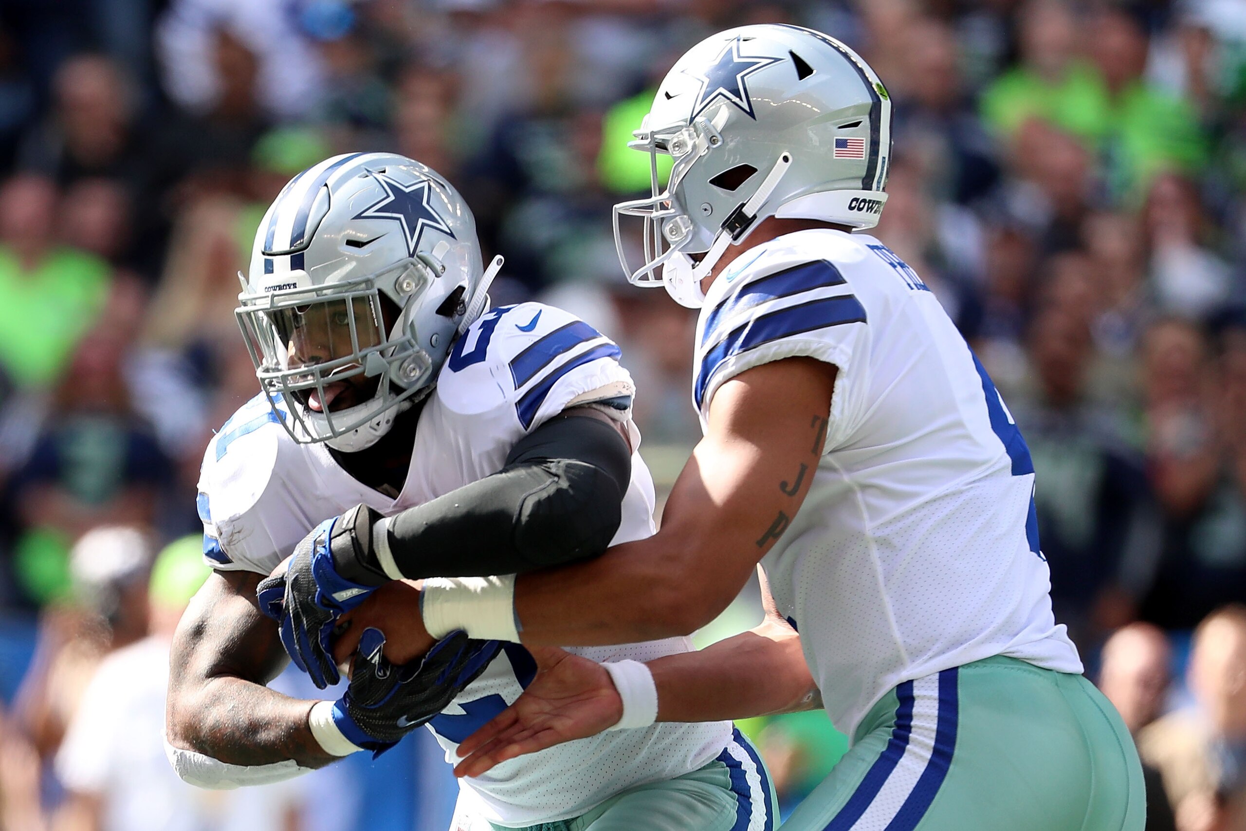 SEATTLE, WA - SEPTEMBER 23: Dak Prescott #4 hands the ball off to Ezekiel Elliott #21 of the Dallas Cowboys in the first quarter against the Seattle Seahawks during their game at CenturyLink Field on September 23, 2018 in Seattle, Washington. (Photo by A SEATTLE, WA - SEPTEMBER 23: Dak Prescott #4 hands the ball off to Ezekiel Elliott #21 of the Dallas Cowboys in the first quarter against the Seattle Seahawks during their game at CenturyLink Field on September 23, 2018 in Seattle, Washington. (Photo by A