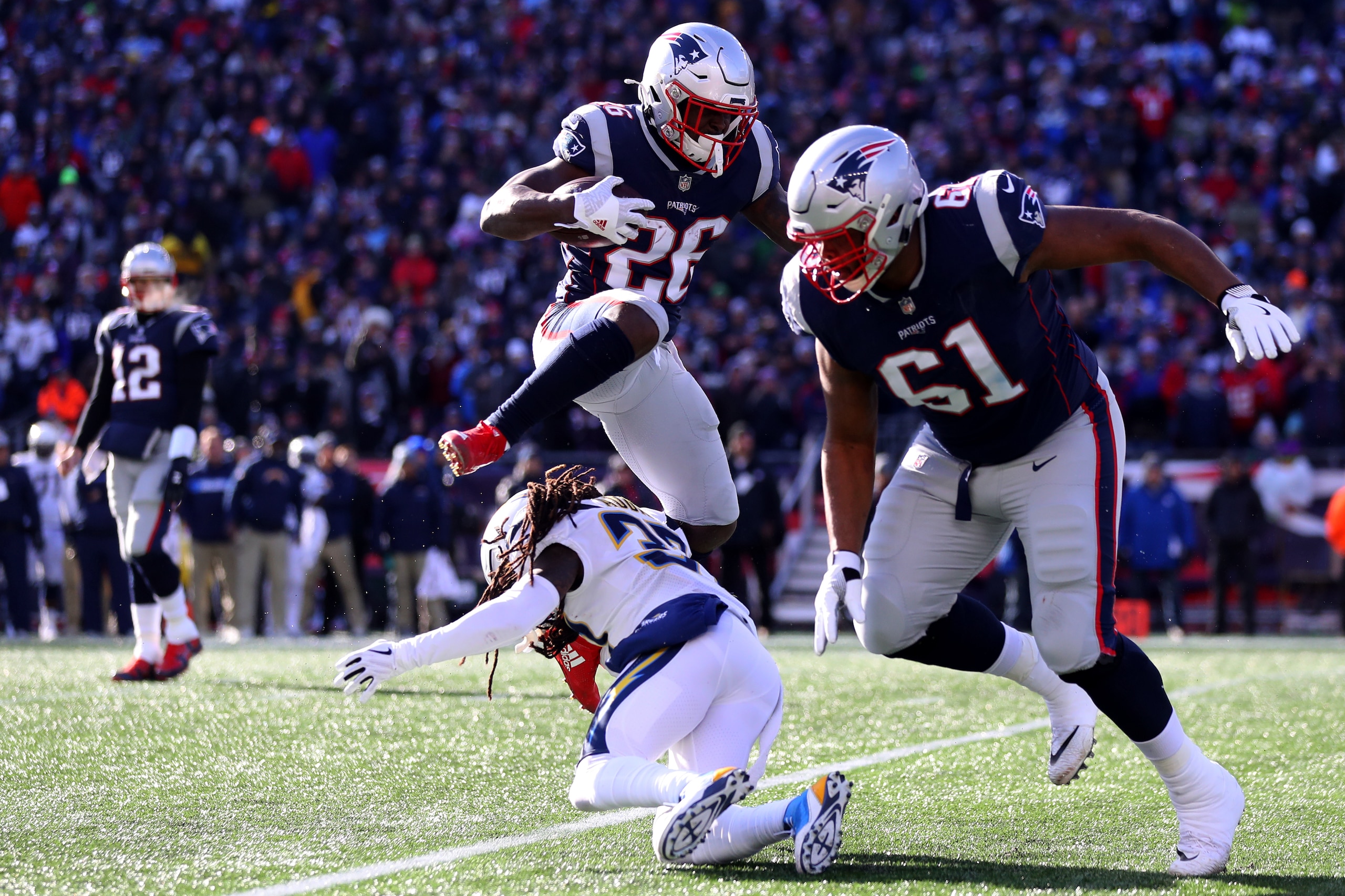 FOXBOROUGH, MASSACHUSETTS - JANUARY 13: Sony Michel #26 of the New England Patriots leaps over Jahleel Addae #37 of the Los Angeles Chargers during the first quarter in the AFC Divisional Playoff Game at Gillette Stadium on January 13, 2019 in Foxborough,
