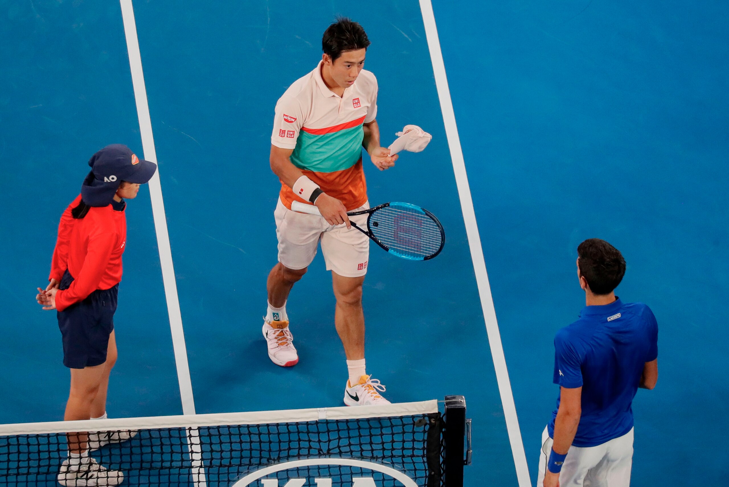 Japan's Kei Nishikori (C) embraces as he leaves the court after retiring from his men's singles quarter-final match against Serbia's Novak Djokovic (L) on day ten of the Australian Open tennis tournament in Melbourne on January 23, 2019. (Photo by DAVID G