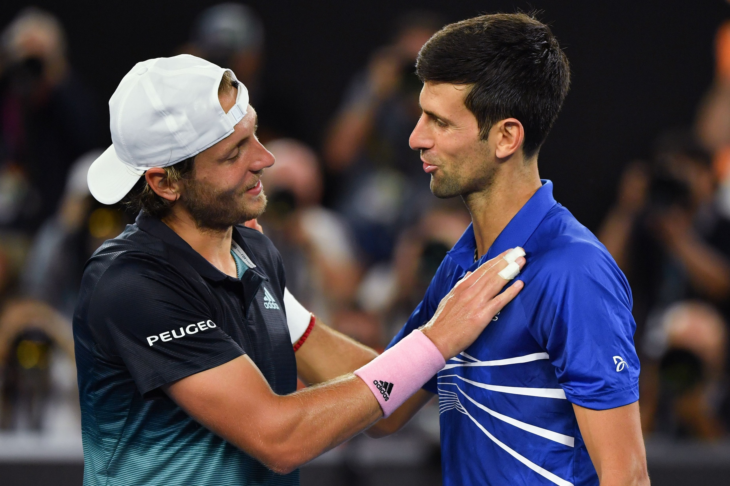 Serbia's Novak Djokovic (R) speaks with France's Lucas Pouille after winning their men's singles semi-final match on day 12 of the Australian Open tennis tournament in Melbourne on January 25, 2019. (Photo by Peter PARKS / AFP) / -- IMAGE RESTRICTED TO ED