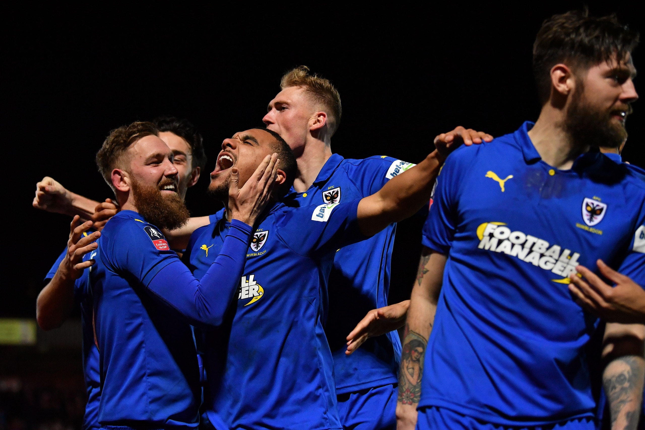AFC Wimbledon's English midfielder Scott Wagstaff (L) celebrates scoring their third goal with AFC Wimbledon's Ghanaian striker Kwesi Appiah (C) during the English FA Cup fourth round football match between AFC Wimbledon and West Ham United at Kingsmeadow