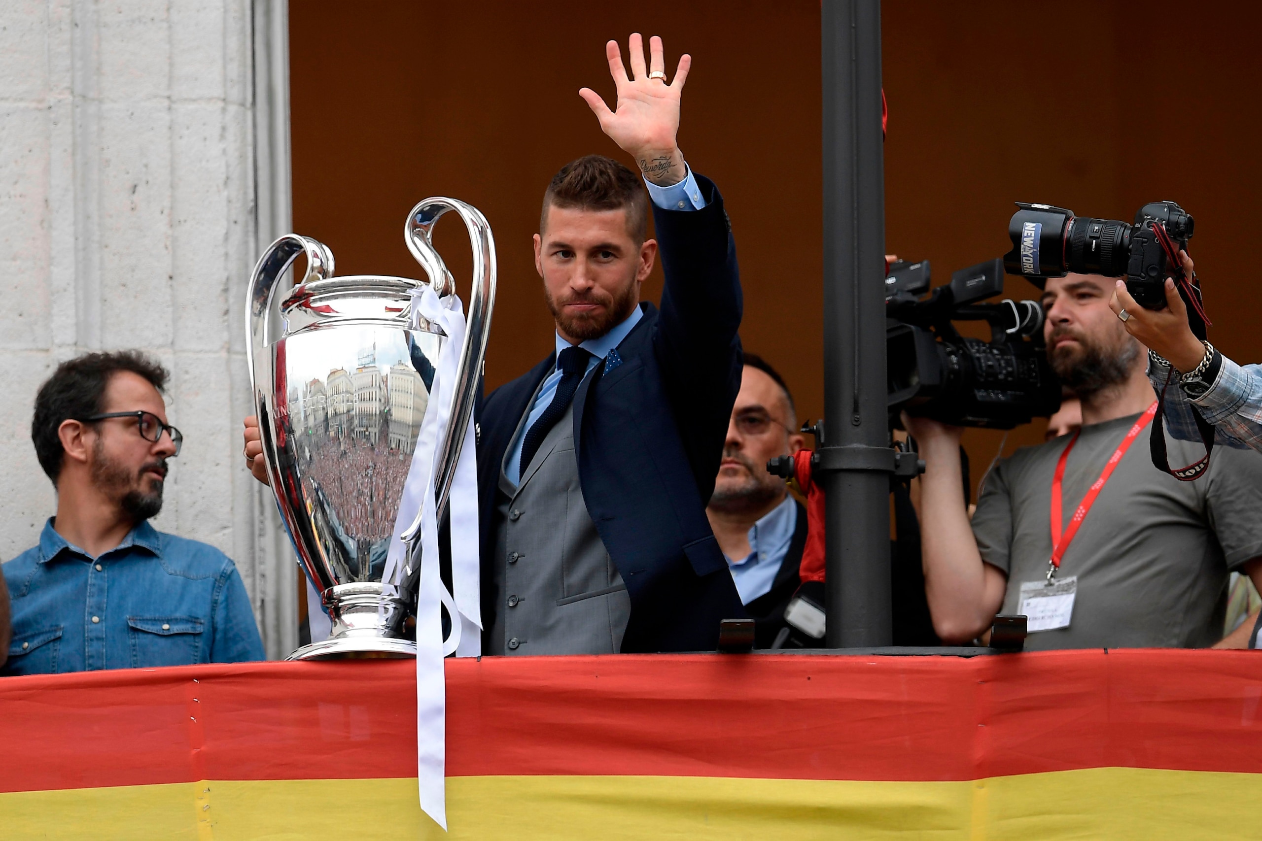 Real Madrid's Spanish defender Sergio Ramos holds the trophy from the balcony of the headquarters of the regional government of Madrid at the Puerta del Sol square in Madrid on May 27, 2018 as players celebrate their third Champions League title in a row 