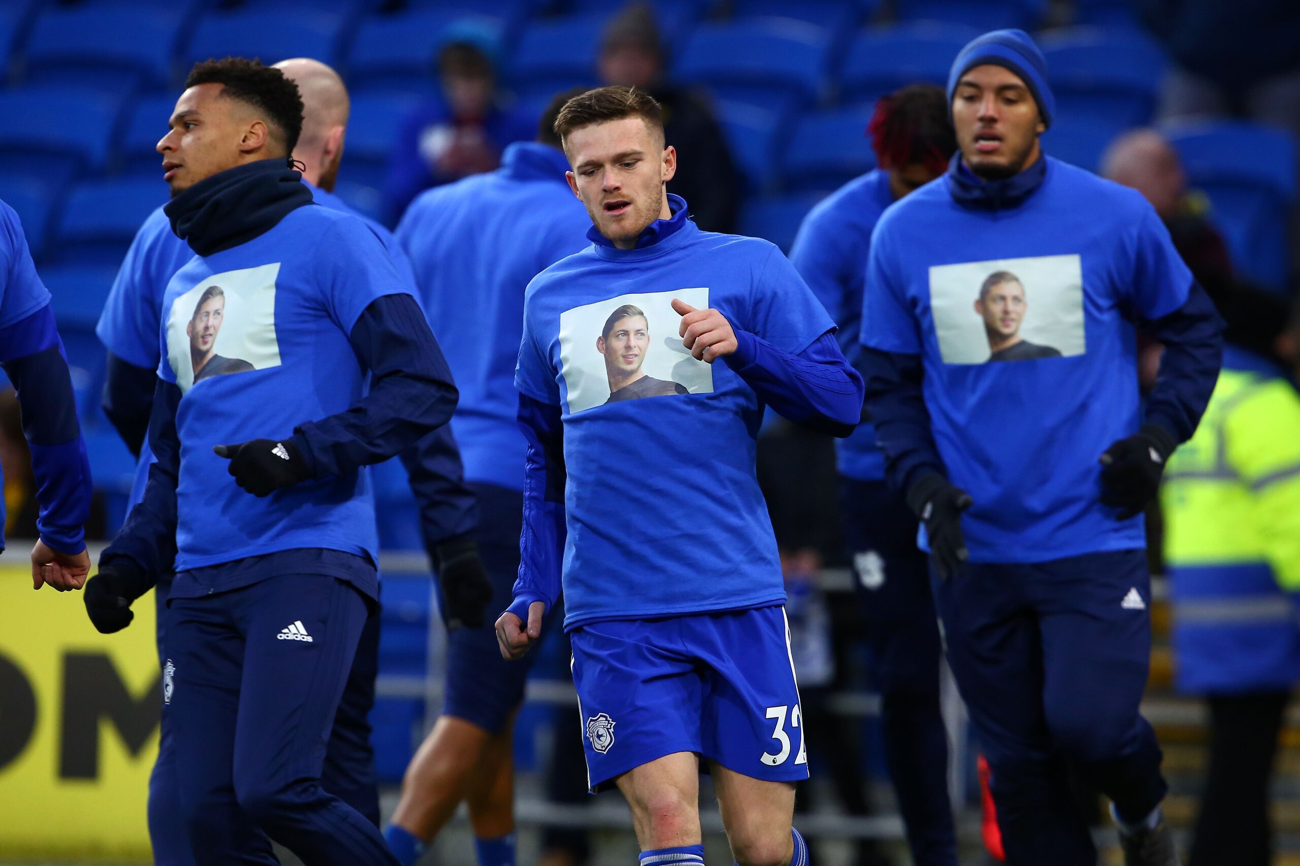 Cardiff City's English striker Rhys Healey (C) and teammates warm up wearing shirts with a picture of the football club's new signing Emiliano Sala, whose flight disappeared from radar over the English Channel north of Guernsey, before the English Premier