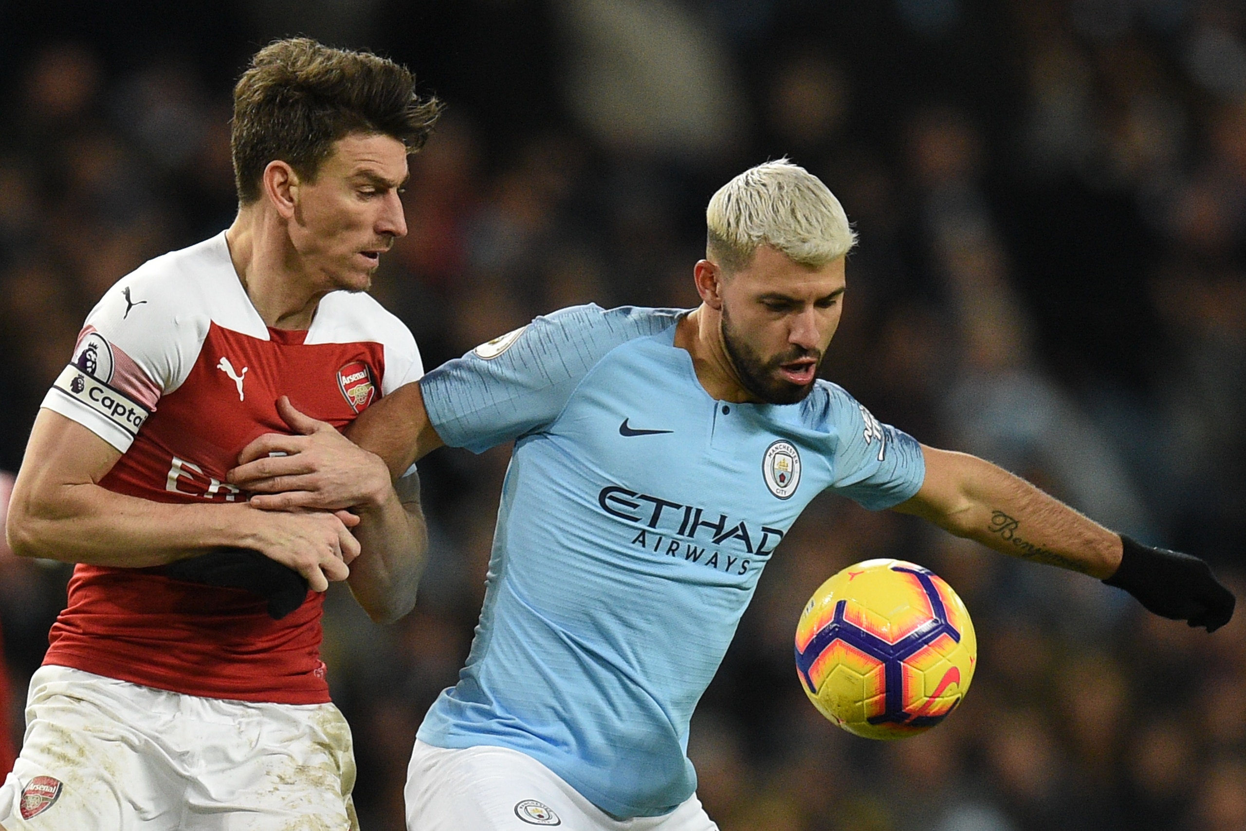 Manchester City's Argentinian striker Sergio Aguero (R) tries to hold off Arsenal's French defender Laurent Koscielny (L) during the English Premier League football match between Manchester City and Arsenal at the Etihad Stadium in Manchester, north west 