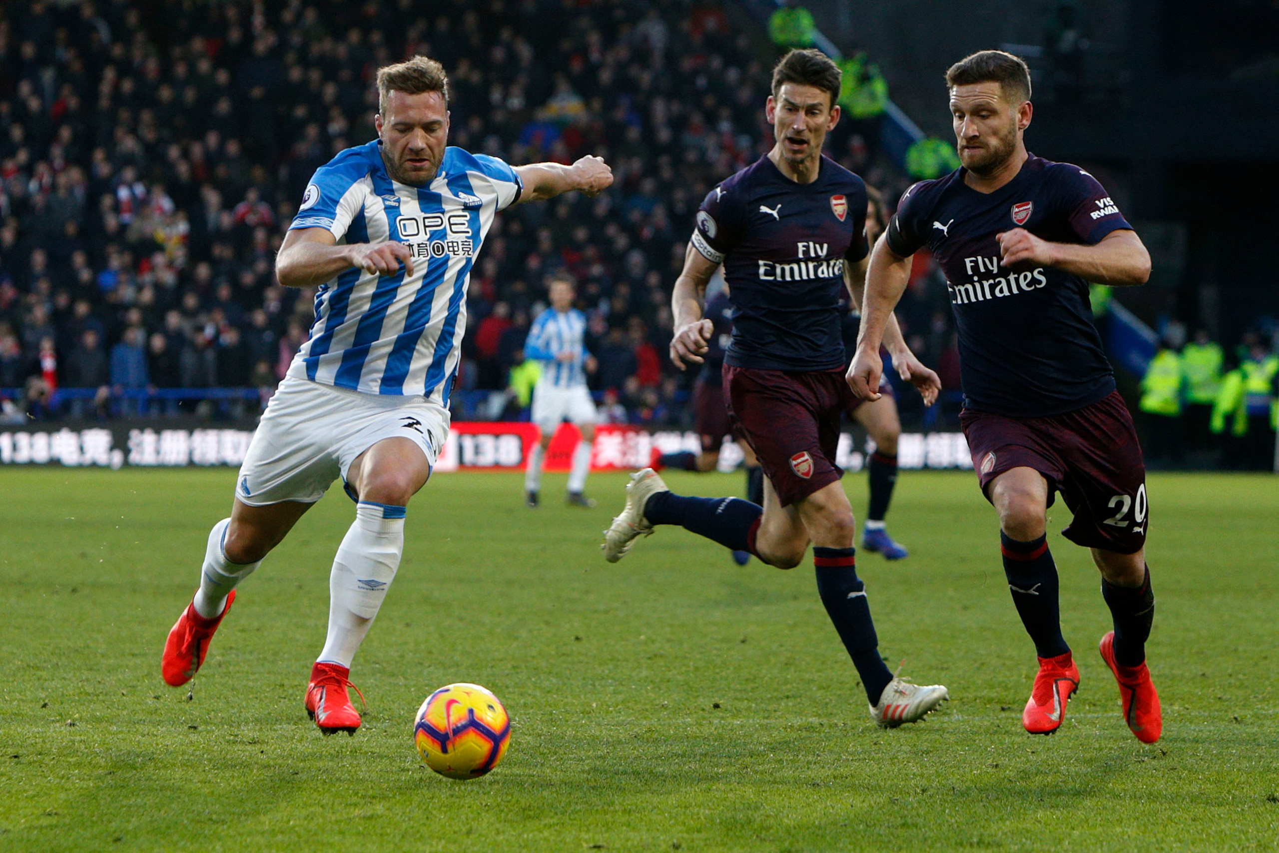 HUDDERSFIELD, ENGLAND - FEBRUARY 09: Laurent Depoitre of Huddersfield Town, Shkodran Mustafi and Laurent Koscielny of Arsenal during the Premier League match between Huddersfield Town and Arsenal FC at John Smith's Stadium on February 09, 2019 in Huddersf