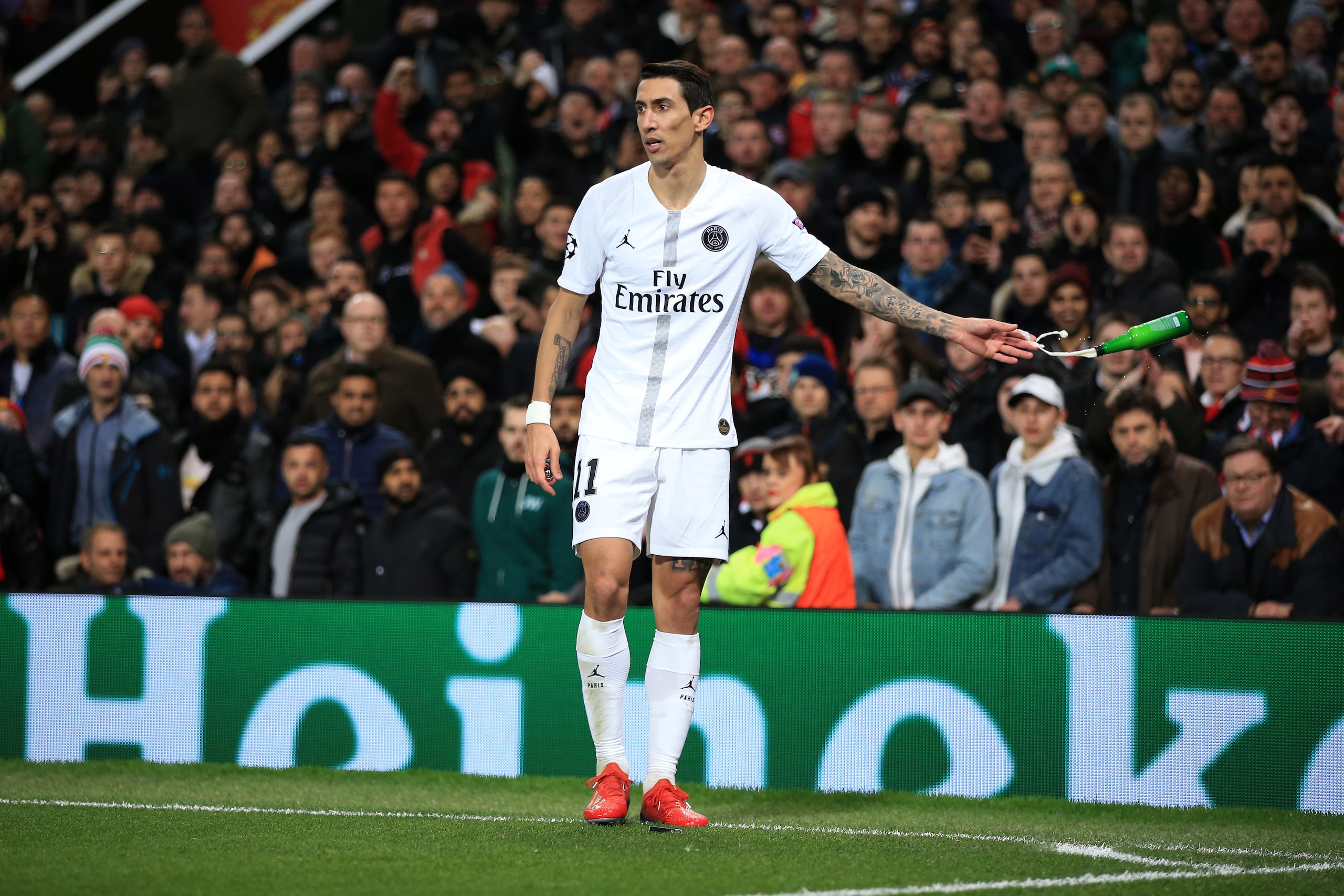 MANCHESTER, ENGLAND - FEBRUARY 12:  Angel Di Maria of Paris Saint-Germain tosses away a bottle of beer thrown by the fans during the UEFA Champions League Round of 16 First Leg match between Manchester United and Paris Saint-Germain at Old Trafford on Feb