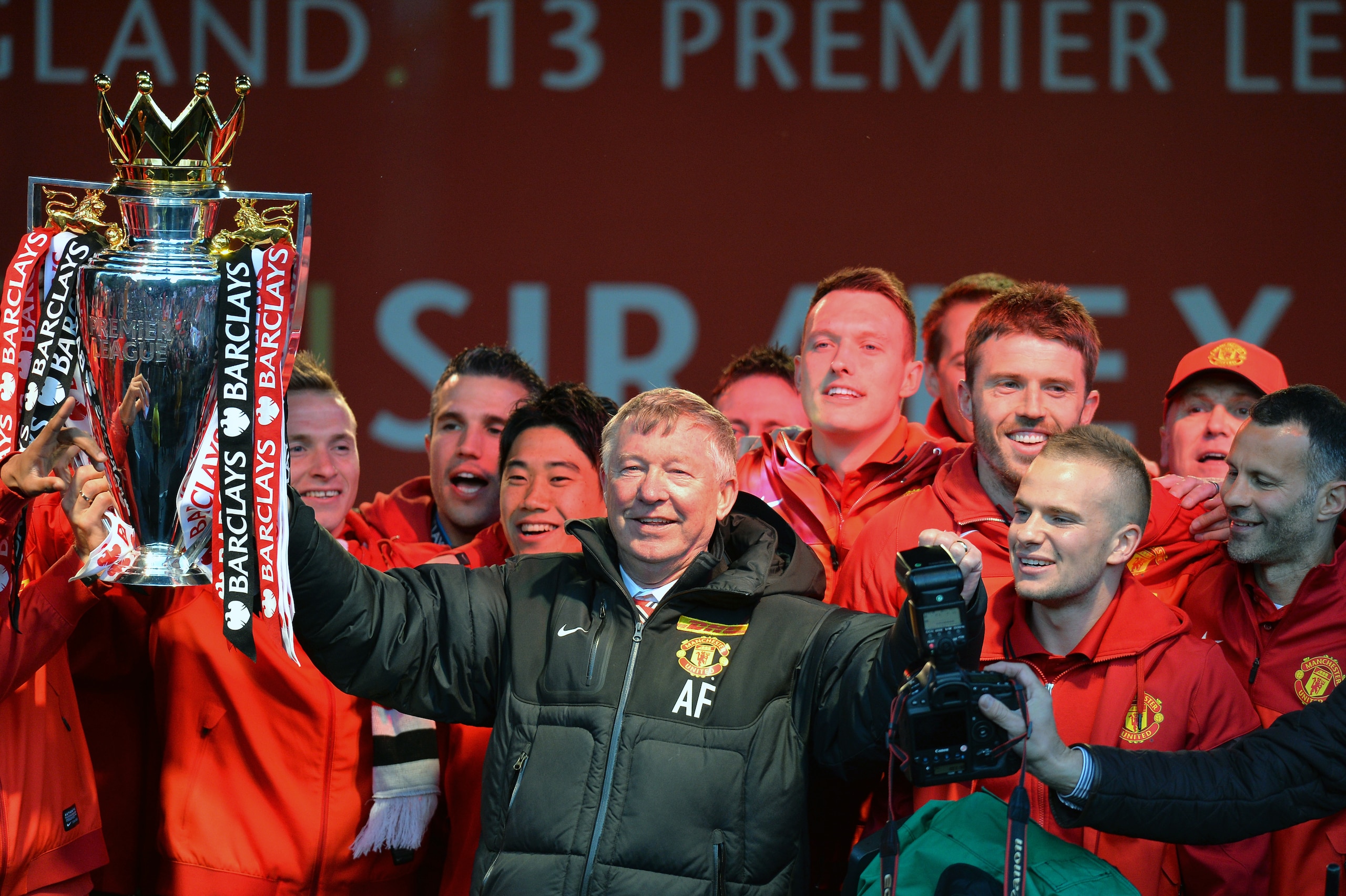 Retiring iconic Manchester United manager Alex Ferguson (C) and his players hold the Premier League trophy outside the town hall in Manchester, north west England, on May 13, 2013 during the team's victory parade to celebrate winning the Premier League fo