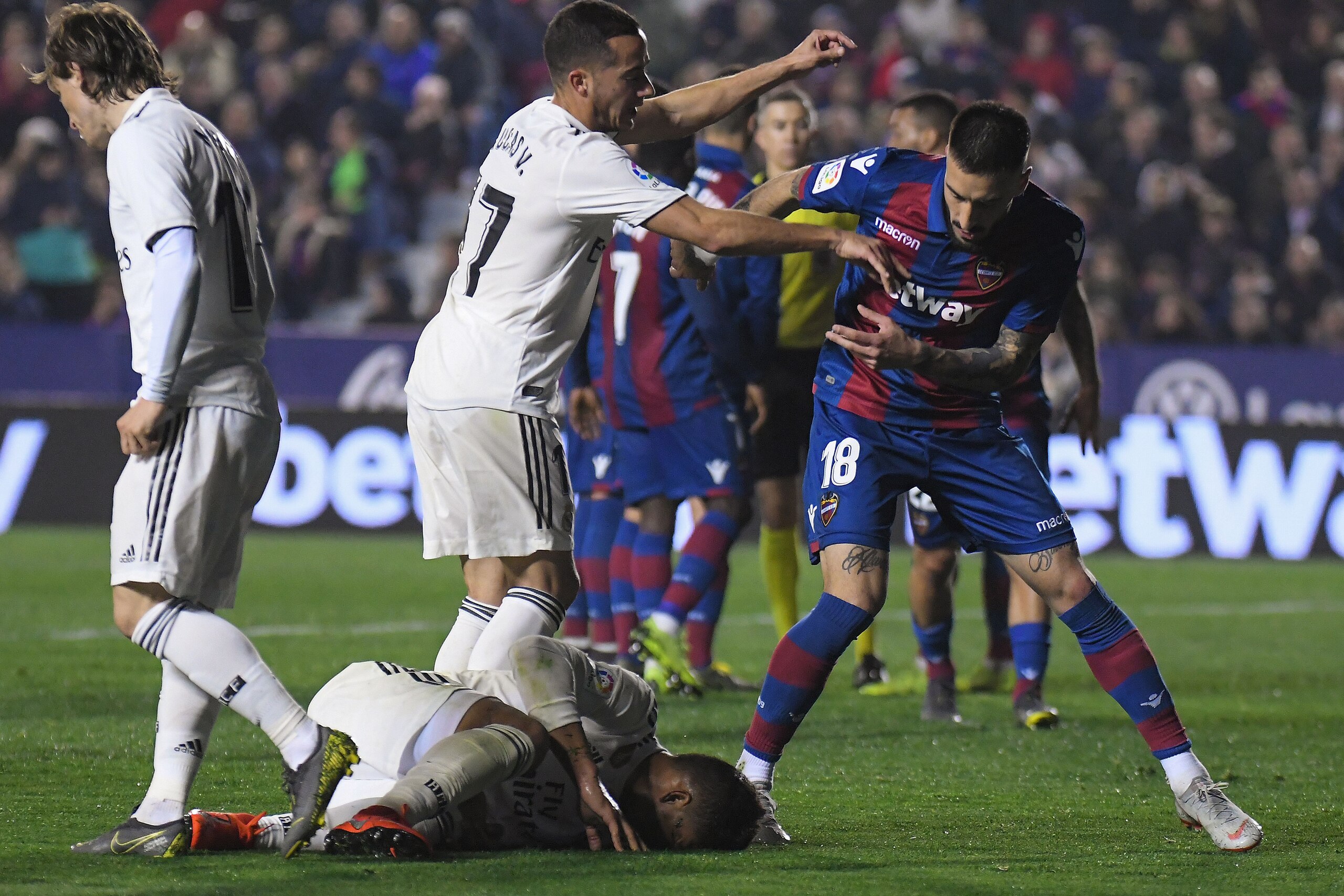 Real Madrid's Spanish midfielder Lucas Vazquez (C) argues with Levante's Uruguayan defender Erick Cabaco (R) as Real Madrid's Brazilian midfielder Casemiro lies on the ground during the Spanish league football match between Levante UD and Real Madrid CF a