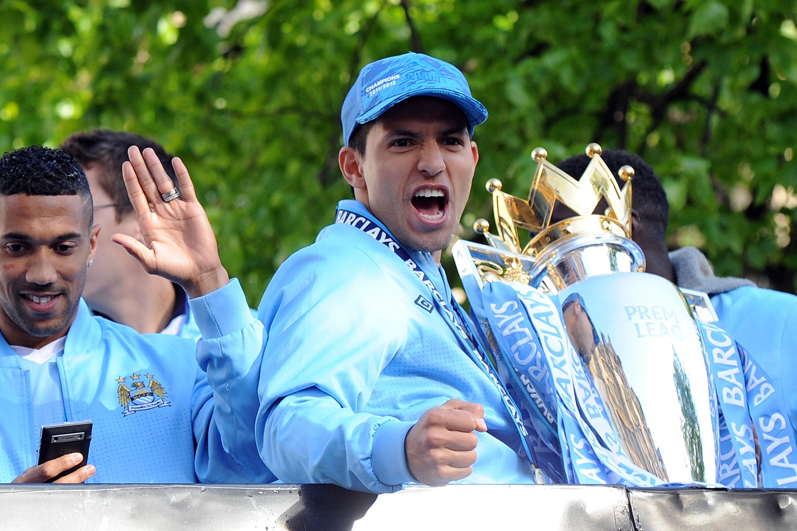 MANCHESTER, ENGLAND - MAY 14:  Sergio Aguero of Manchester City celebrates with the Barclays Premier League trophy next to team-mate Gael Clichy in front of Manchester Town Hall during the victory parade around the streets of Manchester on May 14, 2012 in
