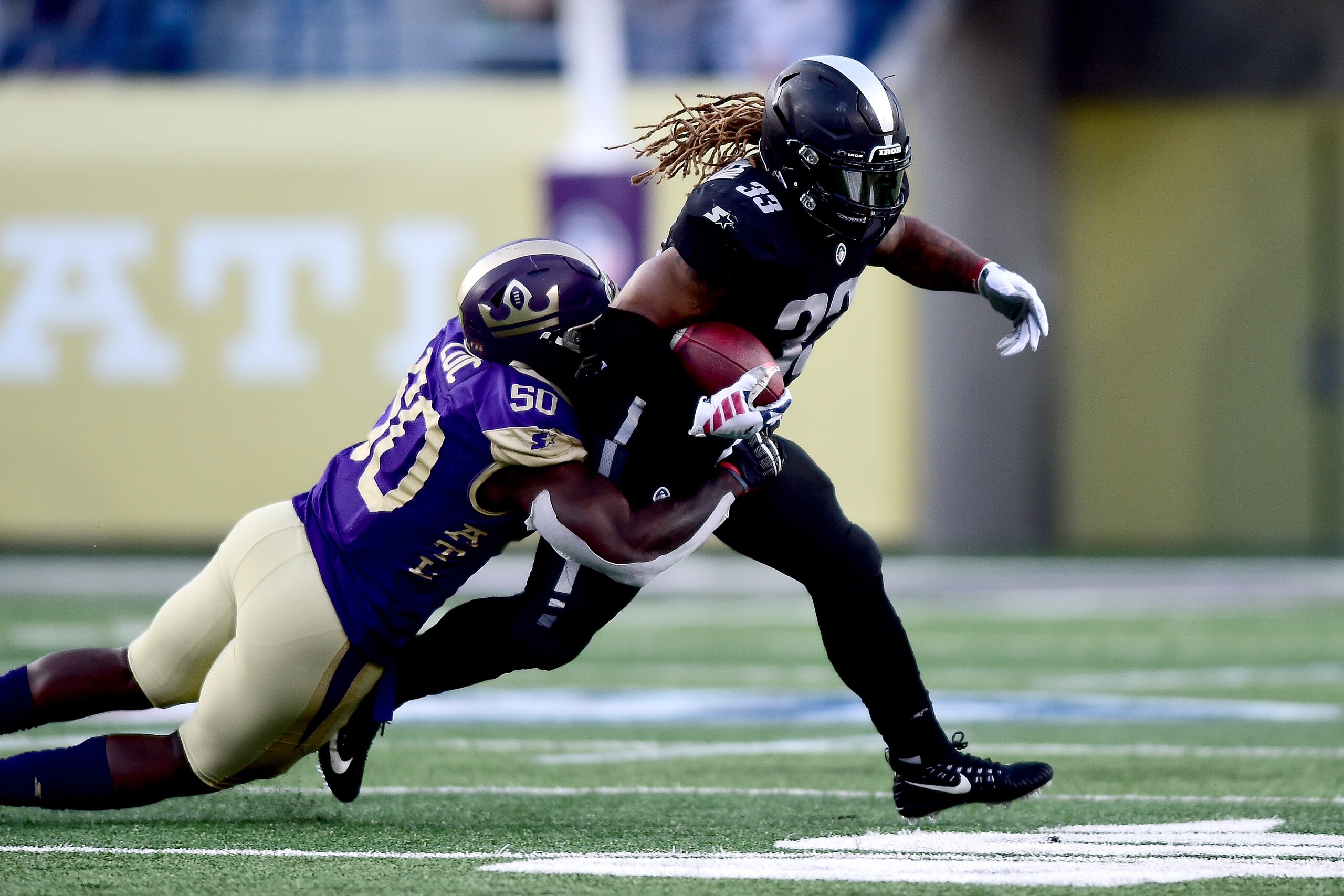 ATLANTA, GEORGIA - FEBRUARY 24:  Trent Richardson #33 of Birmingham Iron is wrapped up by Jeff Luc #50 of Atlanta Legends during the third quarter of the Alliance of American Football game at Georgia State Stadium on February 24, 2019 in Atlanta, Georgia.
