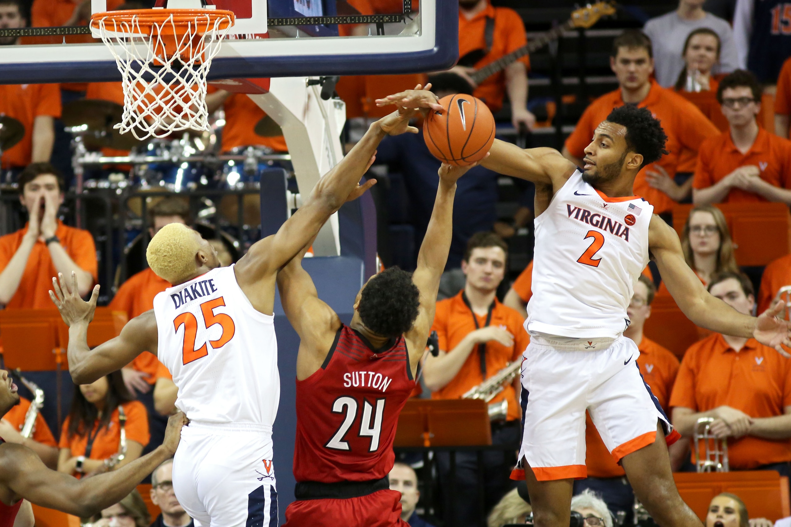 CHARLOTTESVILLE, VA - MARCH 09: Mamadi Diakite #25 and Braxton Key #2 of the Virginia Cavaliers block a shot by Dwayne Sutton #24 of the Louisville Cardinals in the second half during a game at John Paul Jones Arena on March 9, 2019 in Charlottesville, Vi