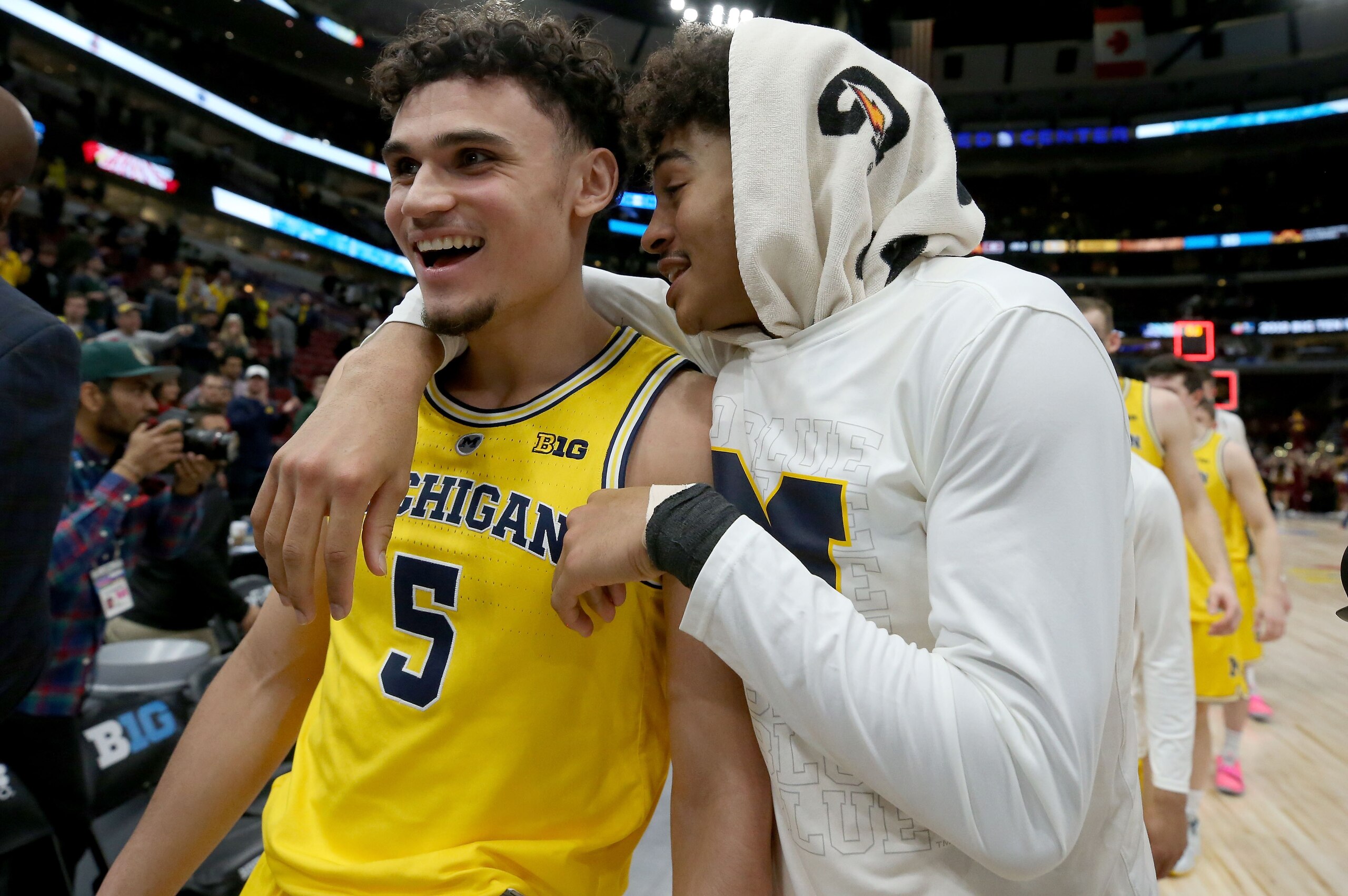 CHICAGO, ILLINOIS - MARCH 16:  Adrien Nunez #5 and Jordan Poole #2 of the Michigan Wolverines walk off the court after beating the Minnesota Golden Gophers 76-49 during the semifinals of the Big Ten Basketball Tournament at the United Center on March 16, 