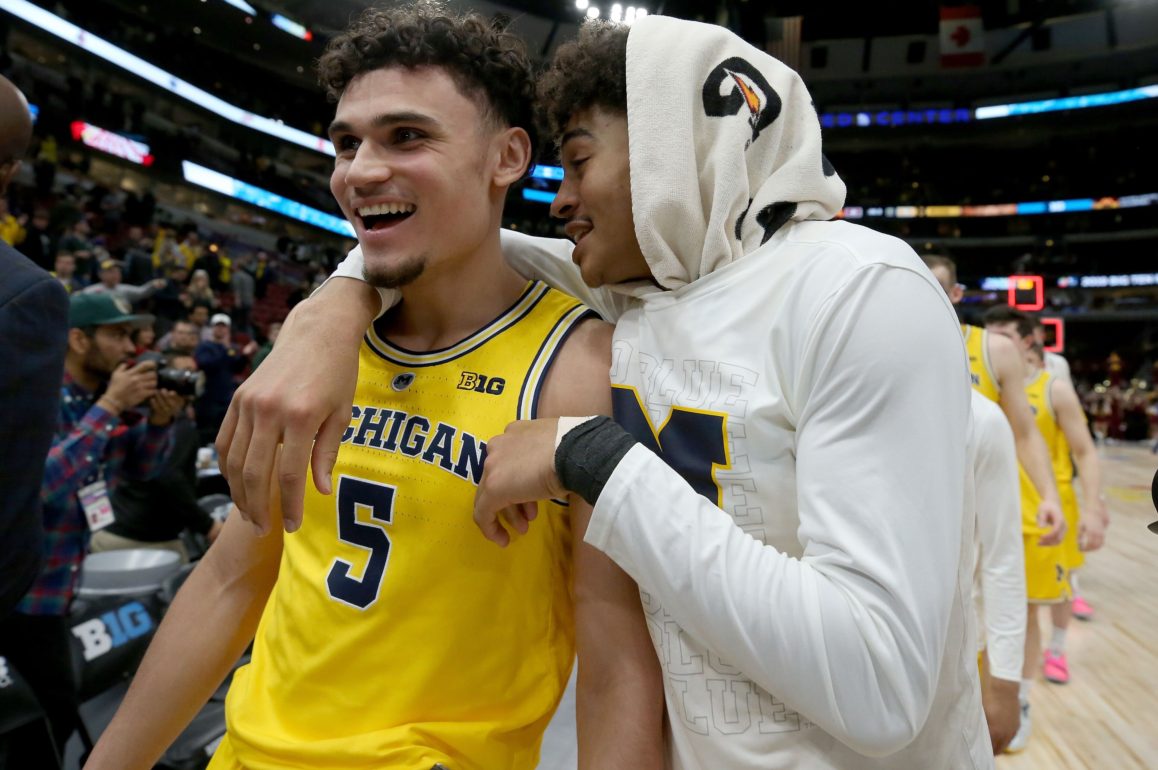 CHICAGO, ILLINOIS - MARCH 16:  Adrien Nunez #5 and Jordan Poole #2 of the Michigan Wolverines walk off the court after beating the Minnesota Golden Gophers 76-49 during the semifinals of the Big Ten Basketball Tournament at the United Center on March 16, 