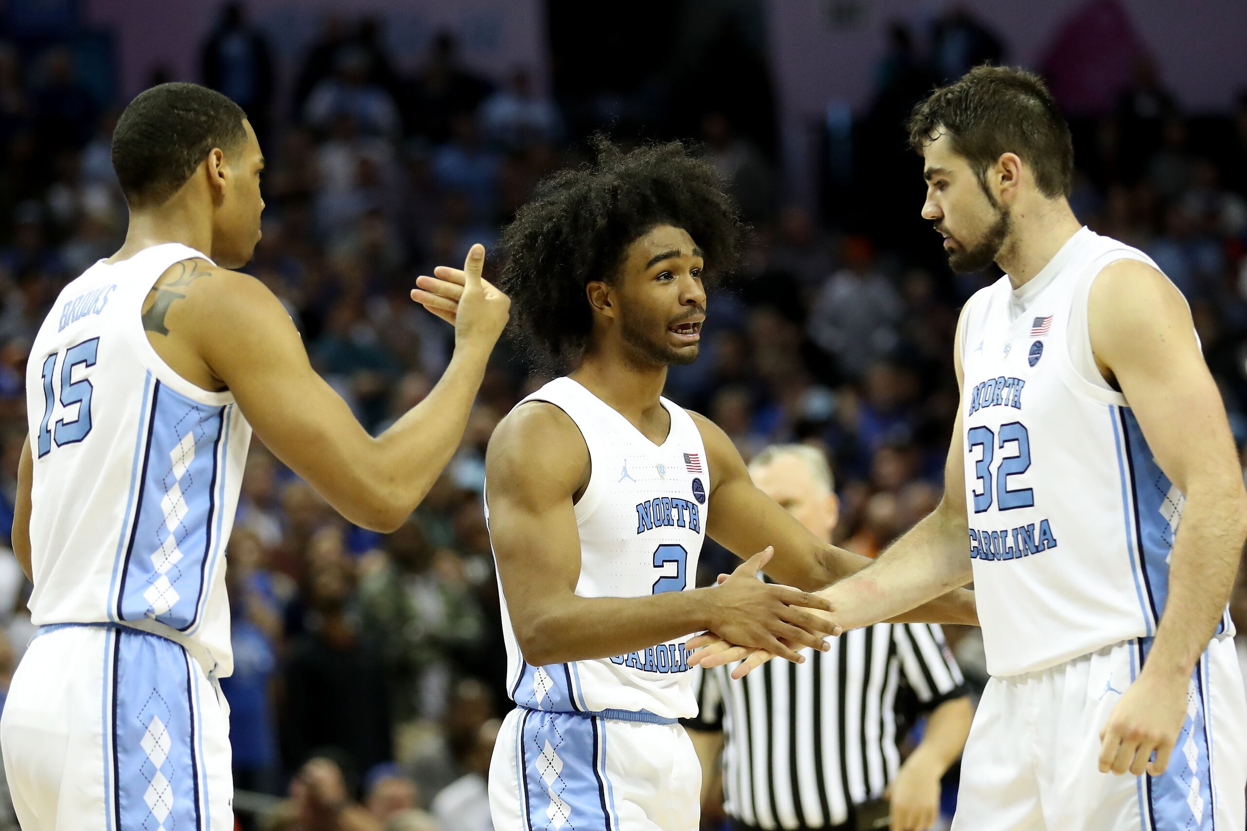 CHARLOTTE, NORTH CAROLINA - MARCH 15: Teammates Garrison Brooks #15, Coby White #2, and Luke Maye #32 of the North Carolina Tar Heels react against the Duke Blue Devils during their game in the semifinals of the 2019 Men's ACC Basketball Tournament at Spe