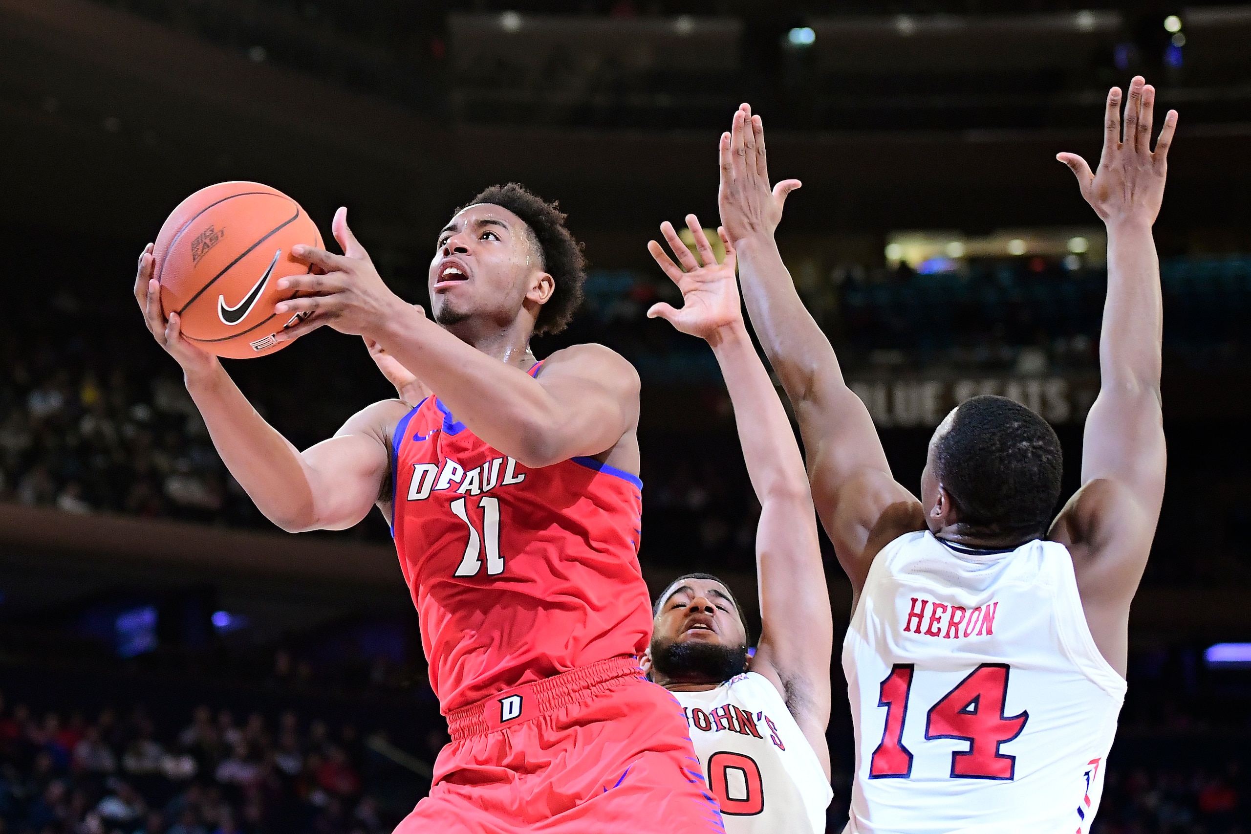 NEW YORK, NEW YORK - MARCH 13:  Eli Cain #11 of the DePaul Blue Demons attempts a lay up past Mustapha Heron #14 of the St. John's Red Storm during the first round of the 2019 Big East men's basketball tournament at Madison Square Garden on March 13, 2019