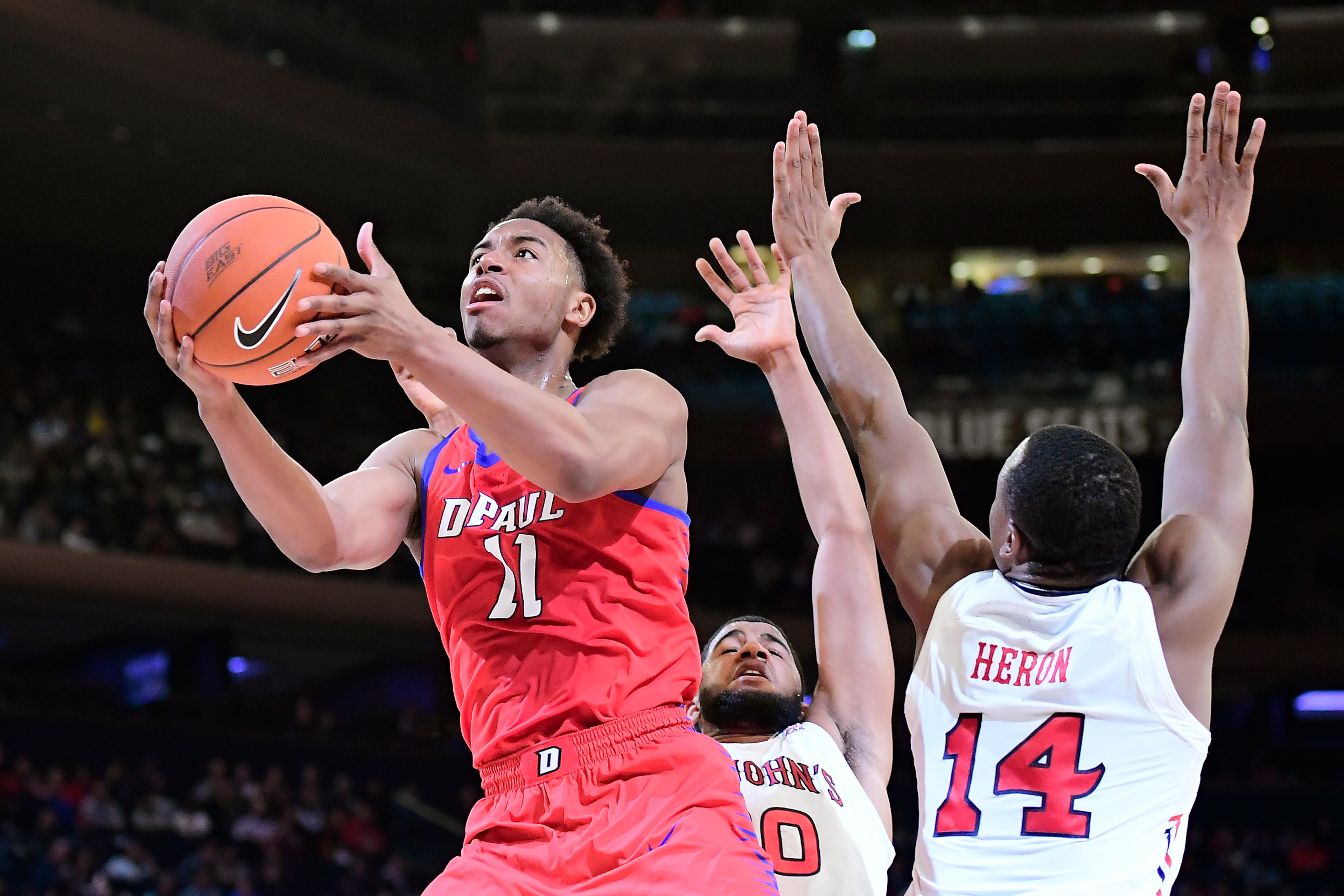 NEW YORK, NEW YORK - MARCH 13:  Eli Cain #11 of the DePaul Blue Demons attempts a lay up past Mustapha Heron #14 of the St. John's Red Storm during the first round of the 2019 Big East men's basketball tournament at Madison Square Garden on March 13, 2019