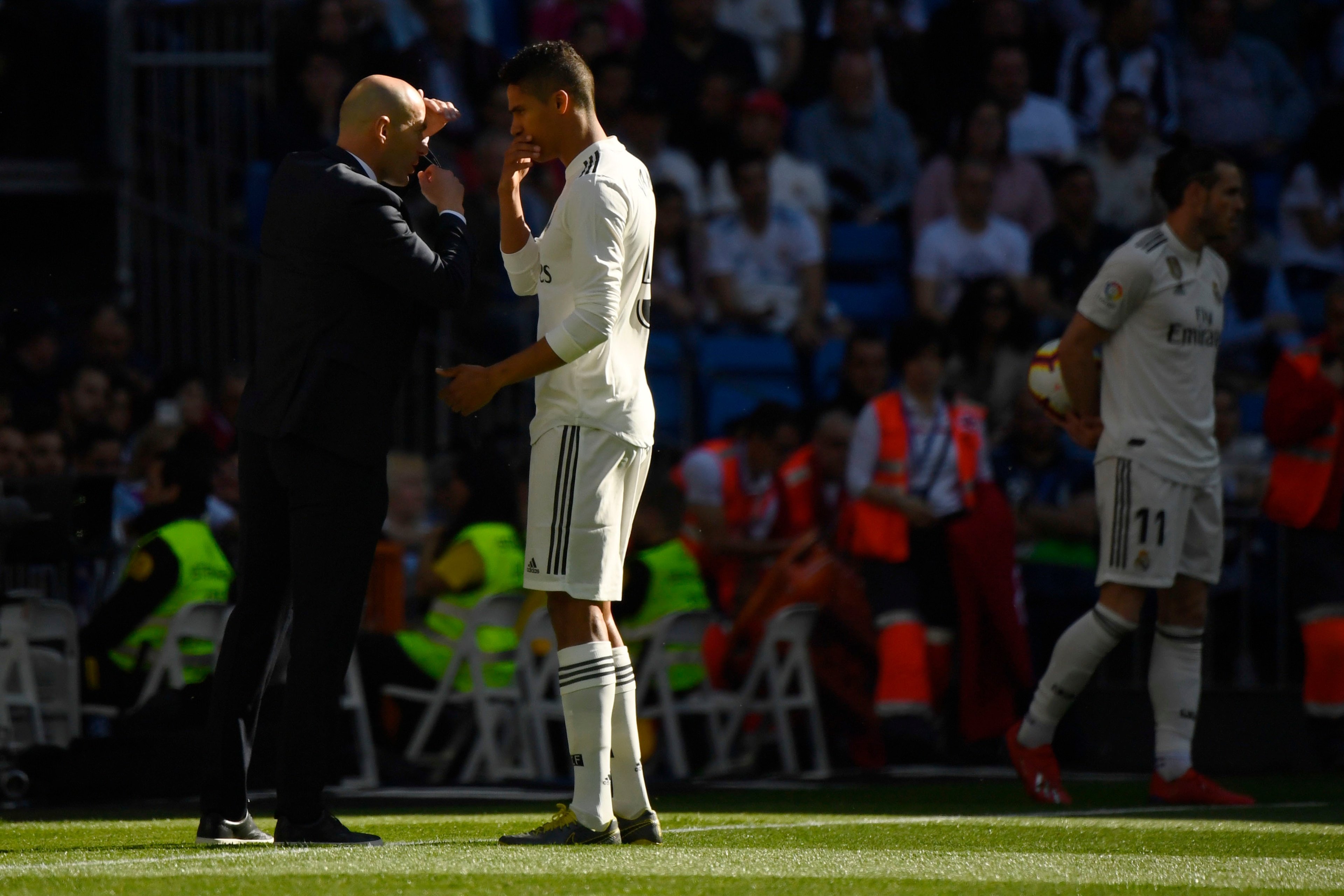 Real Madrid's French coach Zinedine Zidane talks to Real Madrid's French defender Raphael Varane during the Spanish league football match between Real Madrid CF and RC Celta de Vigo at the Santiago Bernabeu stadium in Madrid on March 16, 2019. (Photo by G