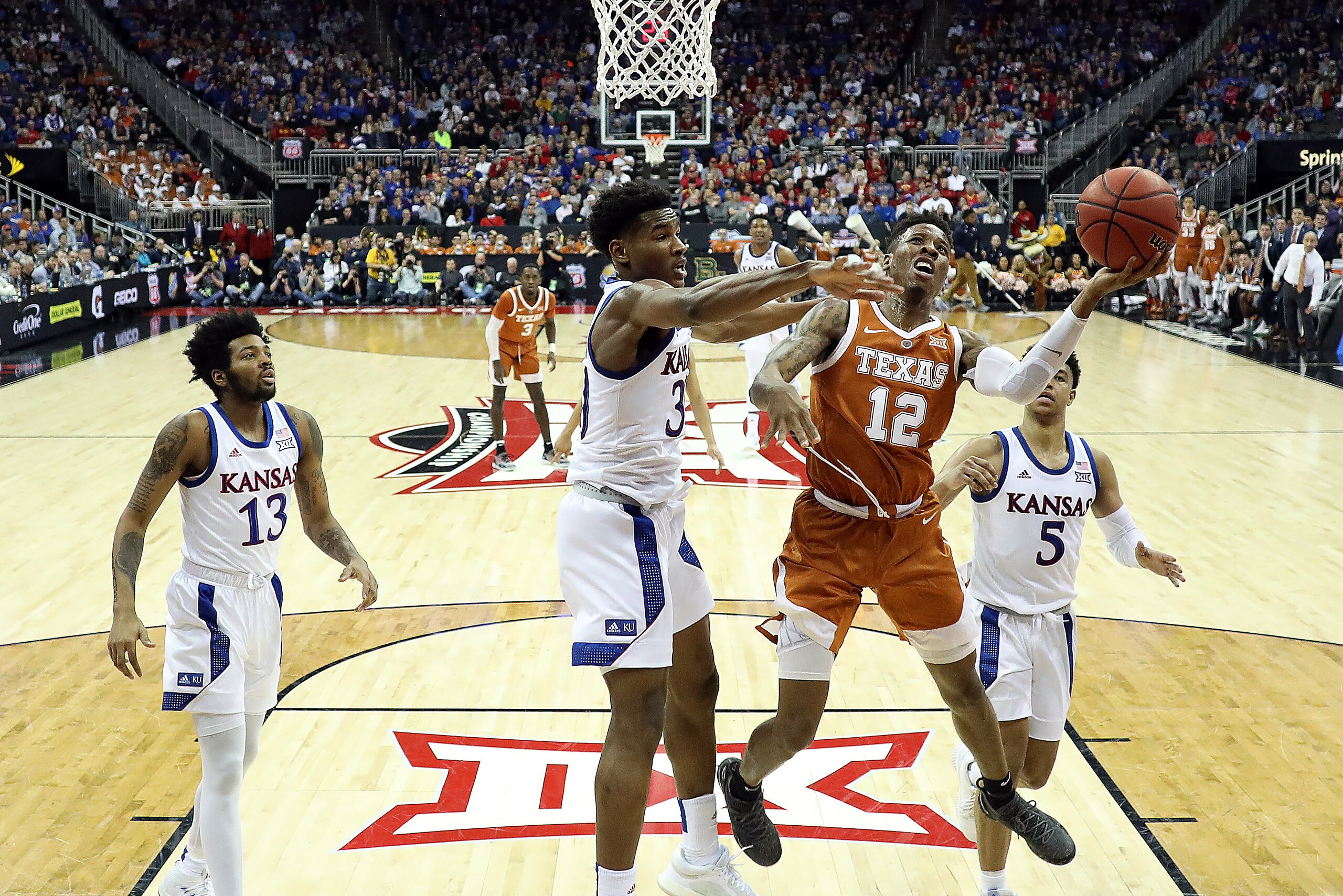 KANSAS CITY, MISSOURI - MARCH 14:  Kerwin Roach II #12 of the Texas Longhorns drives to the basket as Ochai Agbaji #30 of the Kansas Jayhawks defends during the quarterfinal game of the Big 12 Basketball Tournament at Sprint Center on March 14, 2019 in Ka