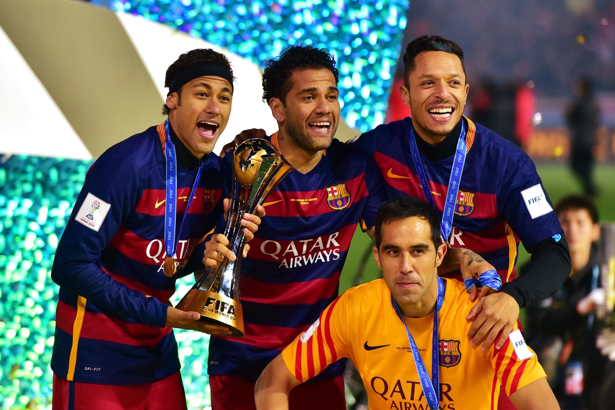 FC Barcelona players, Neymar (L), Dani Alves (C), Adriano (R) and Claudio Bravo (yellow) smile as they hold the trophy of the FIFA Club World Cup at the FIFA Club World Cup final in Yokohama, suburban Tokyo on December 20, 2015. FC Barcelona defeated Rive