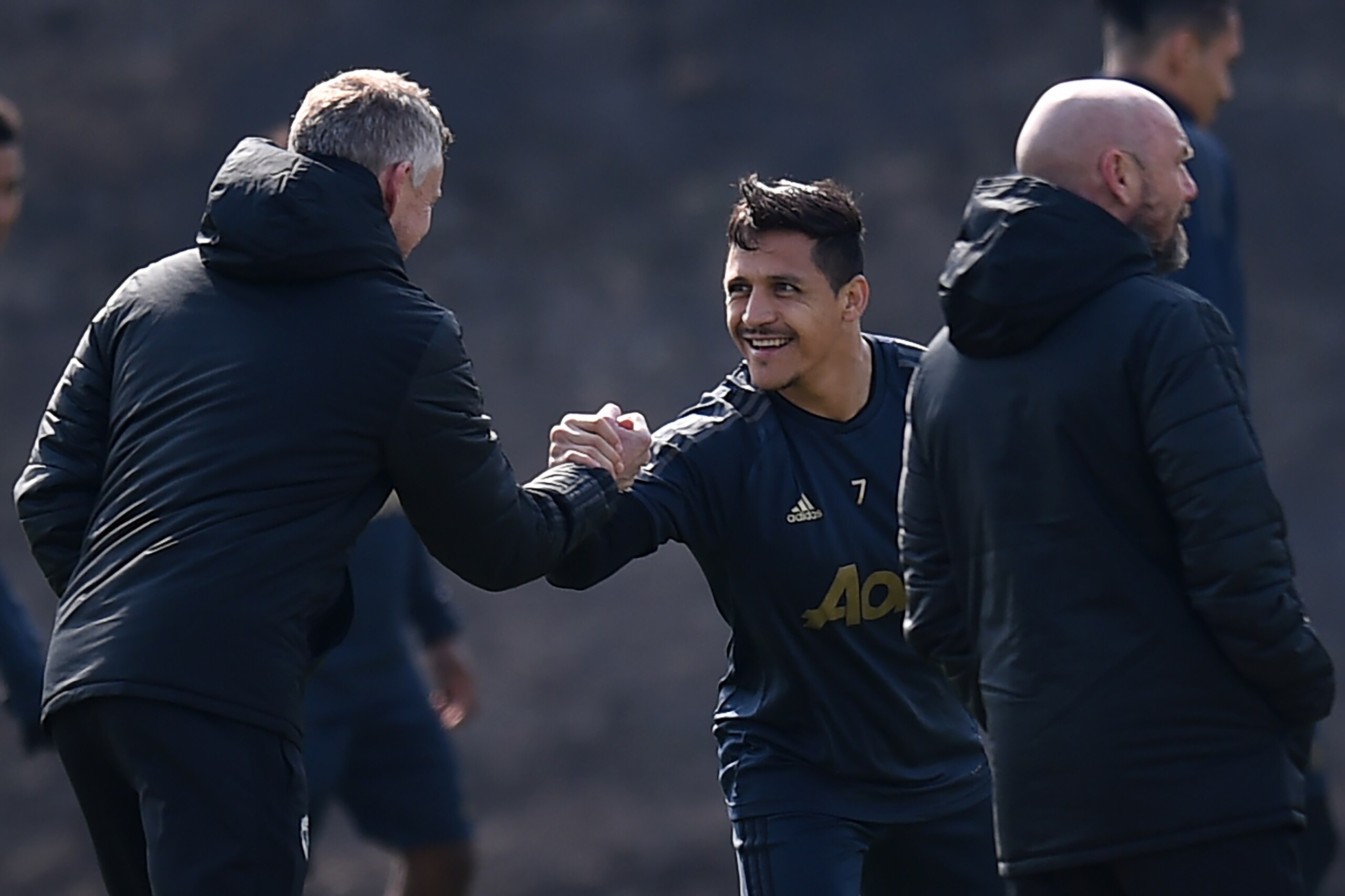 Manchester United's Chilean forward Alexis Sanchez (C) shakes hands with Manchester United's Norwegian manager Ole Gunnar Solskjaer during a training session at the Carrington training ground in greater Manchester, north west England on April 9, 2019, on 