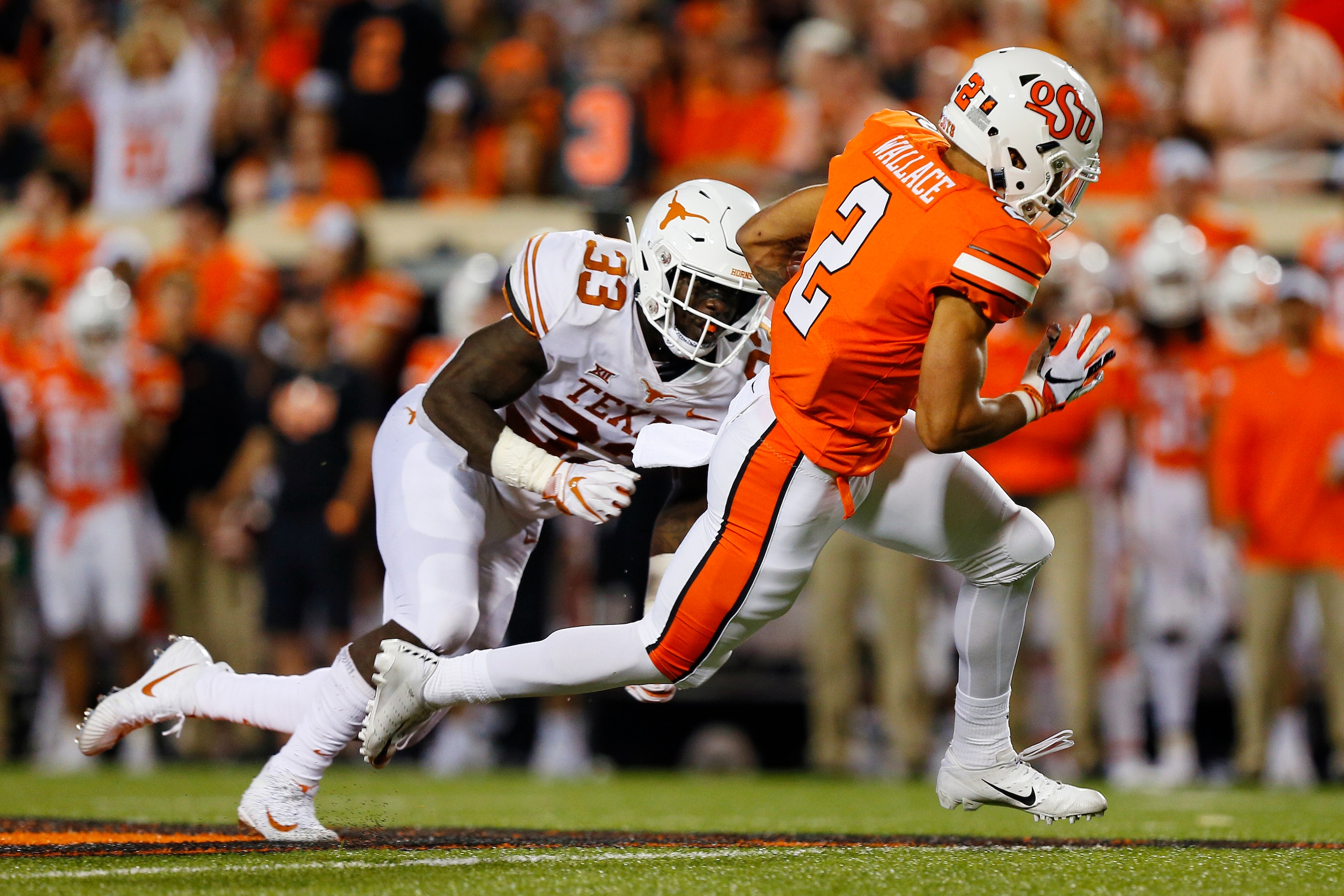 STILLWATER, OK - OCTOBER 27: Wide receiver Tylan Wallace #2 of the Oklahoma State Cowboys takes a catch for 23 yards against linebacker Gary Johnson #33 of the Texas Longhorns in the second quarter on October 27, 2018 at Boone Pickens Stadium in Stillwat STILLWATER, OK - OCTOBER 27: Wide receiver Tylan Wallace #2 of the Oklahoma State Cowboys takes a catch for 23 yards against linebacker Gary Johnson #33 of the Texas Longhorns in the second quarter on October 27, 2018 at Boone Pickens Stadium in Stillwat