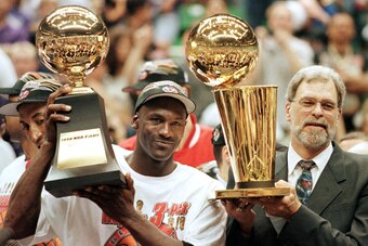 SALT LAKE CITY, UNITED STATES:  Michael Jordan (L) and Chicago Bulls head coach Phil Jackson (R) Most Valuable Player trophy (L) and the Larry O'Brian trophy (R) 14 June after winning game six of the NBA Finals with the Utah Jazz at the Delta Center in Sa