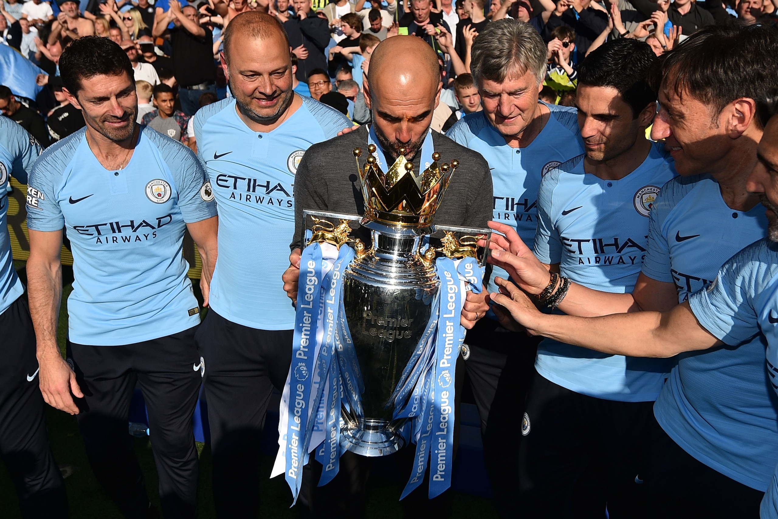 Manchester City's Spanish manager Pep Guardiola (C) kisses the Premier League trophy as he poses with his back-room staff after their 4-1 victory in the English Premier League football match between Brighton and Hove Albion and Manchester City at the Amer