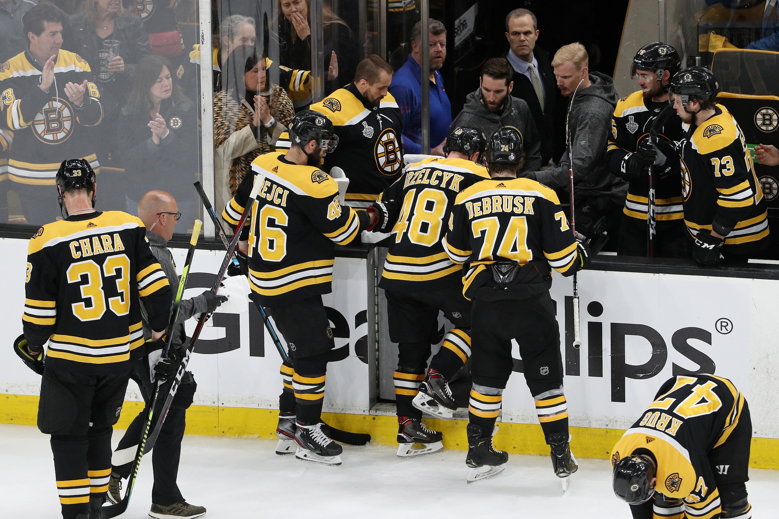 BOSTON, MASSACHUSETTS - MAY 29:  Matt Grzelcyk #48 of the Boston Bruins is taken off the ice by the trainer after being hit into the boards by Oskar Sundqvist (not pictured) #70 of the St. Louis Blues during the first period in Game Two of the 2019 NHL St