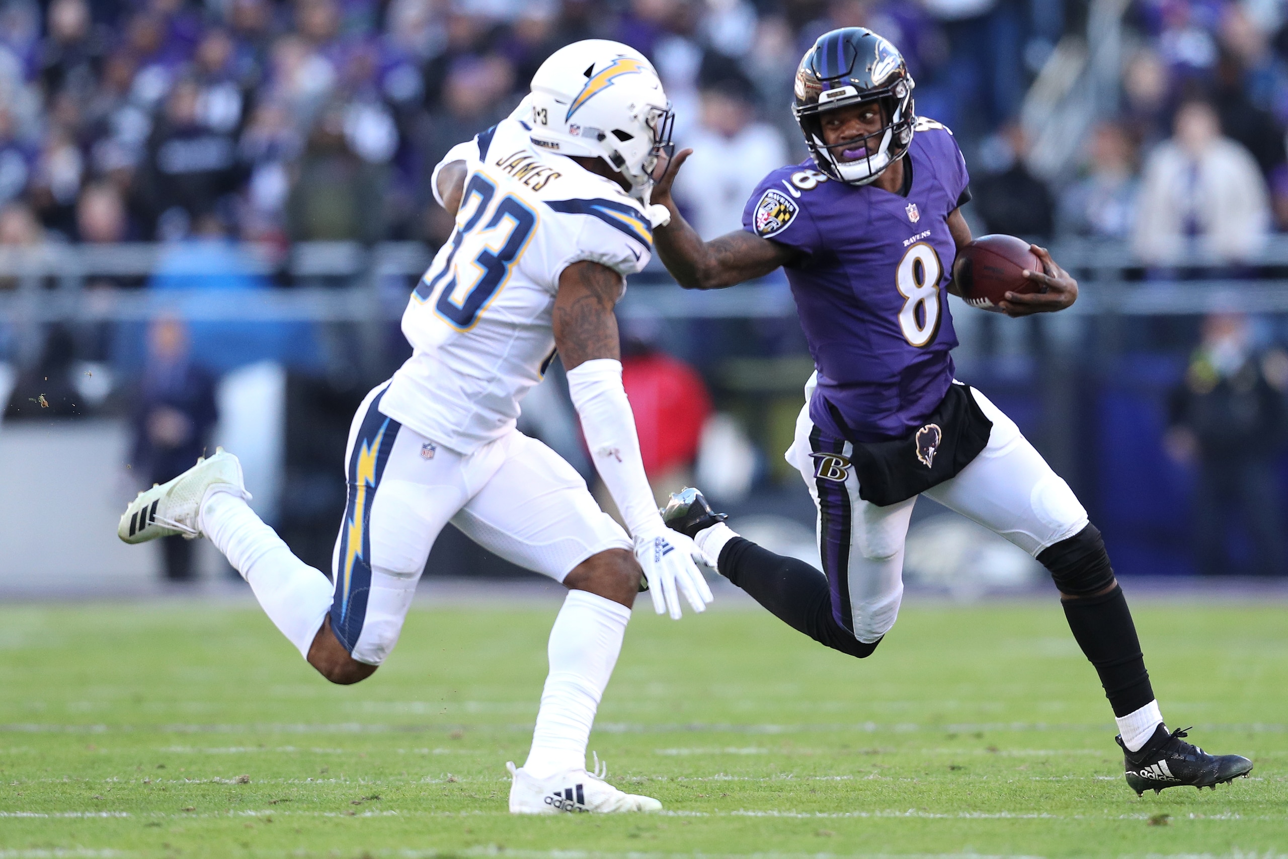 BALTIMORE, MARYLAND - JANUARY 06: Quarterback Lamar Jackson #8 of the Baltimore Ravens stiff arms free safety Derwin James #33 of the Los Angeles Chargers in the second half during the AFC Wild Card Playoff game at M&T Bank Stadium on January 06, 2019 in 